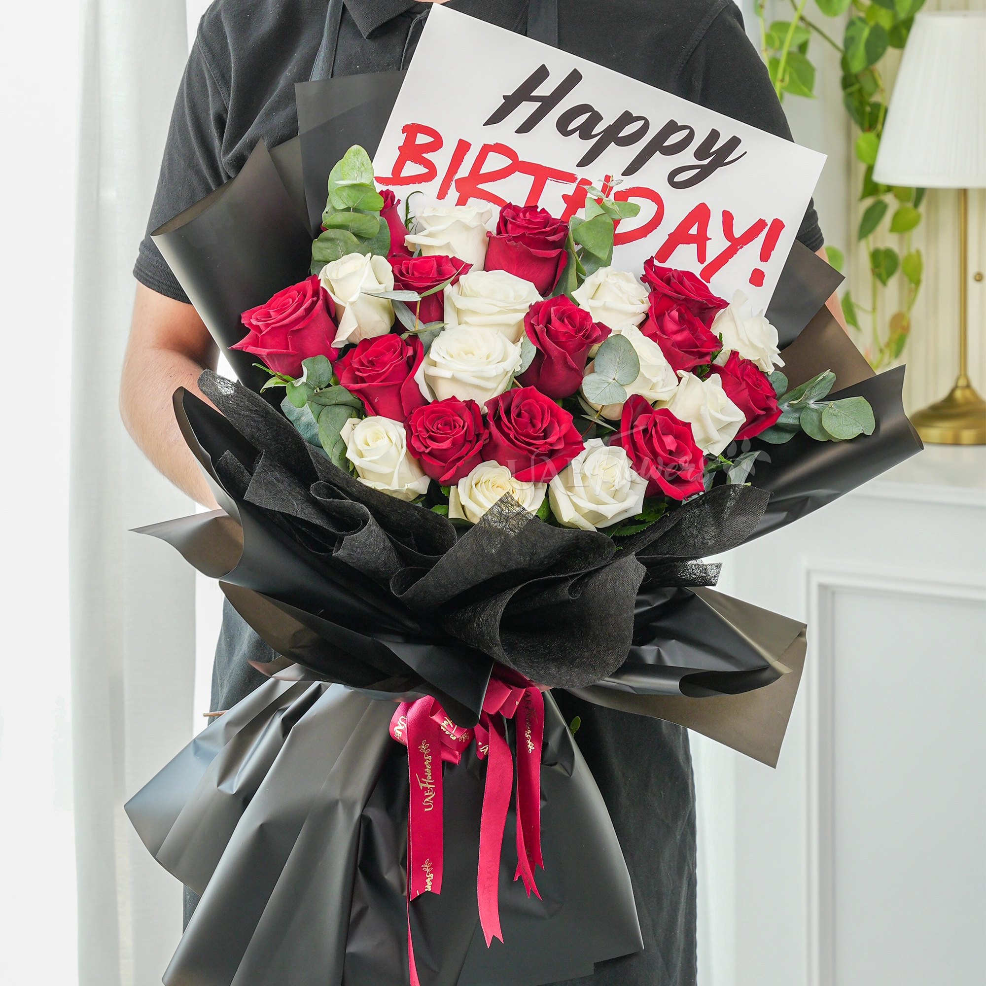 Bouquet of 20 red and white roses with green fillers in black wrapping with Happy Birthday Paper.