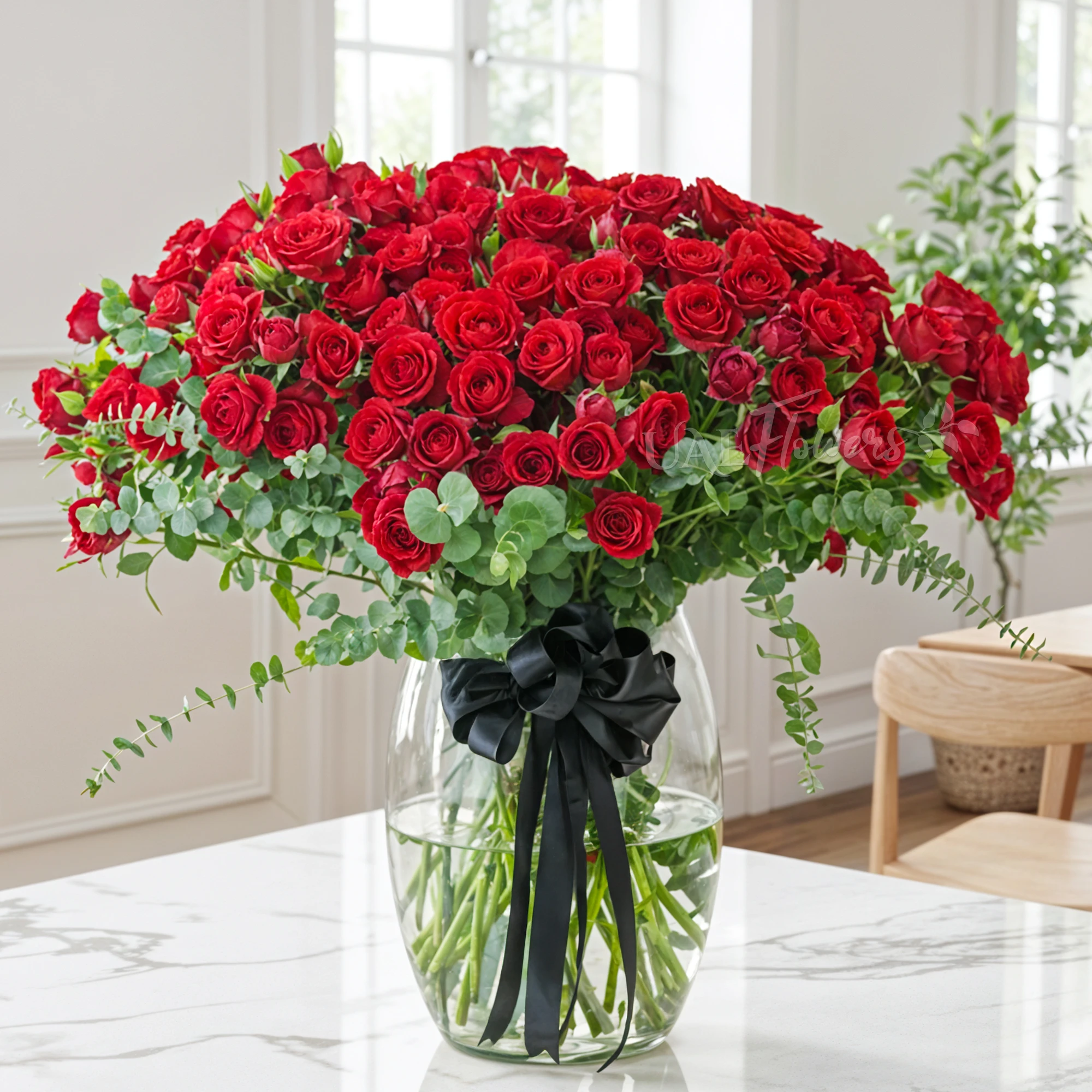 40 red spray roses with eucalyptus in a glass vase.