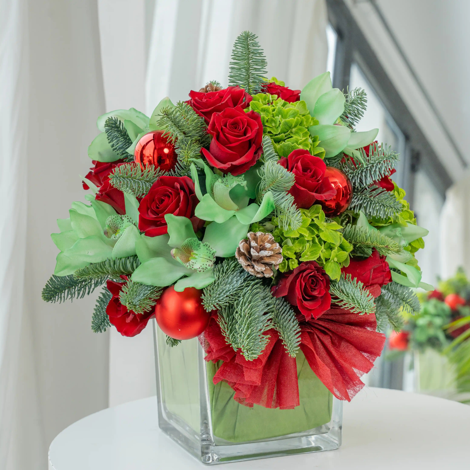 10 red roses, 1 green hydrangea, 1 green cymbidium orchid, Ornaments balls, pinecones, and fillers in a glass vase