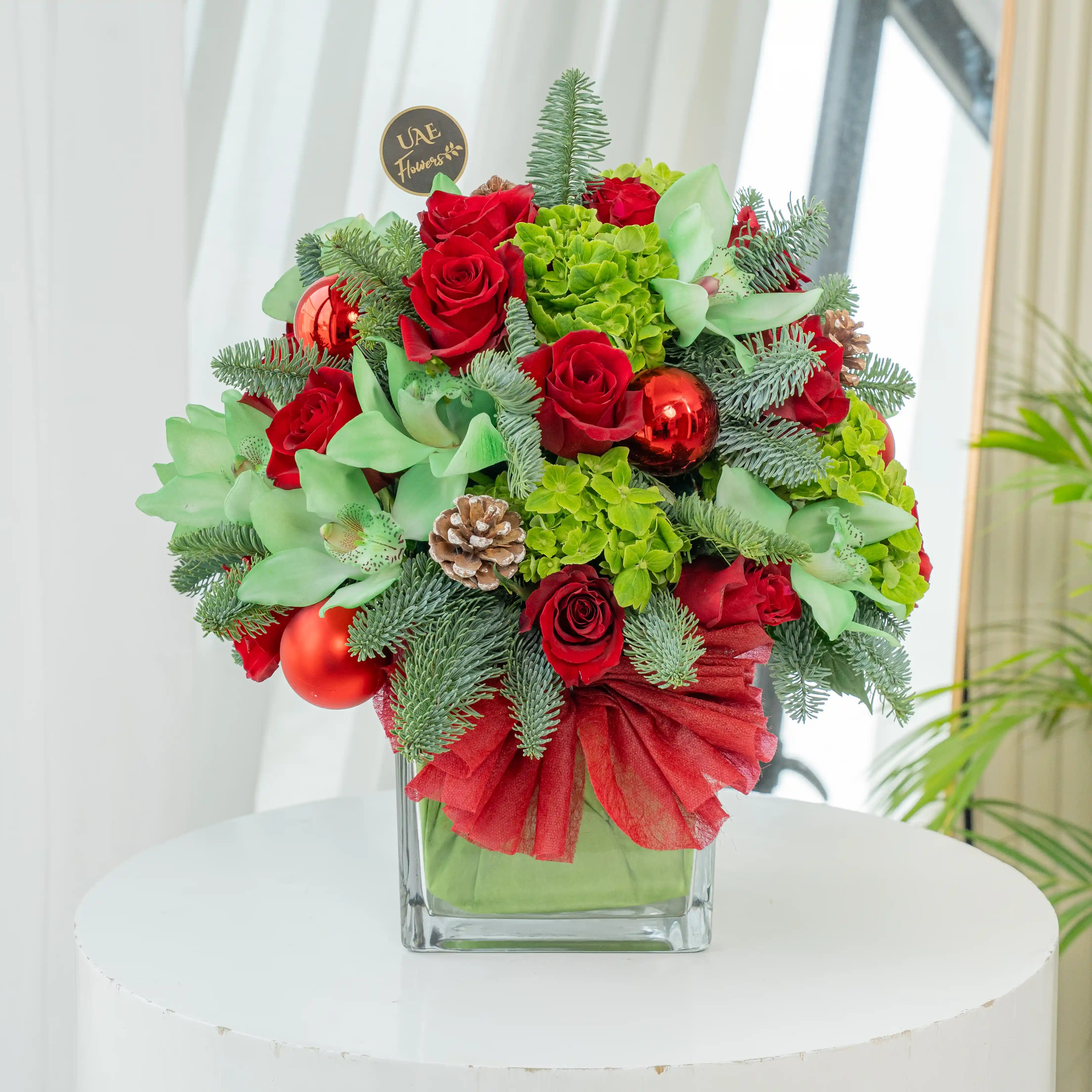 10 red roses, 1 green hydrangea, 1 green cymbidium orchid, Ornaments balls, pinecones, and fillers in a glass vase