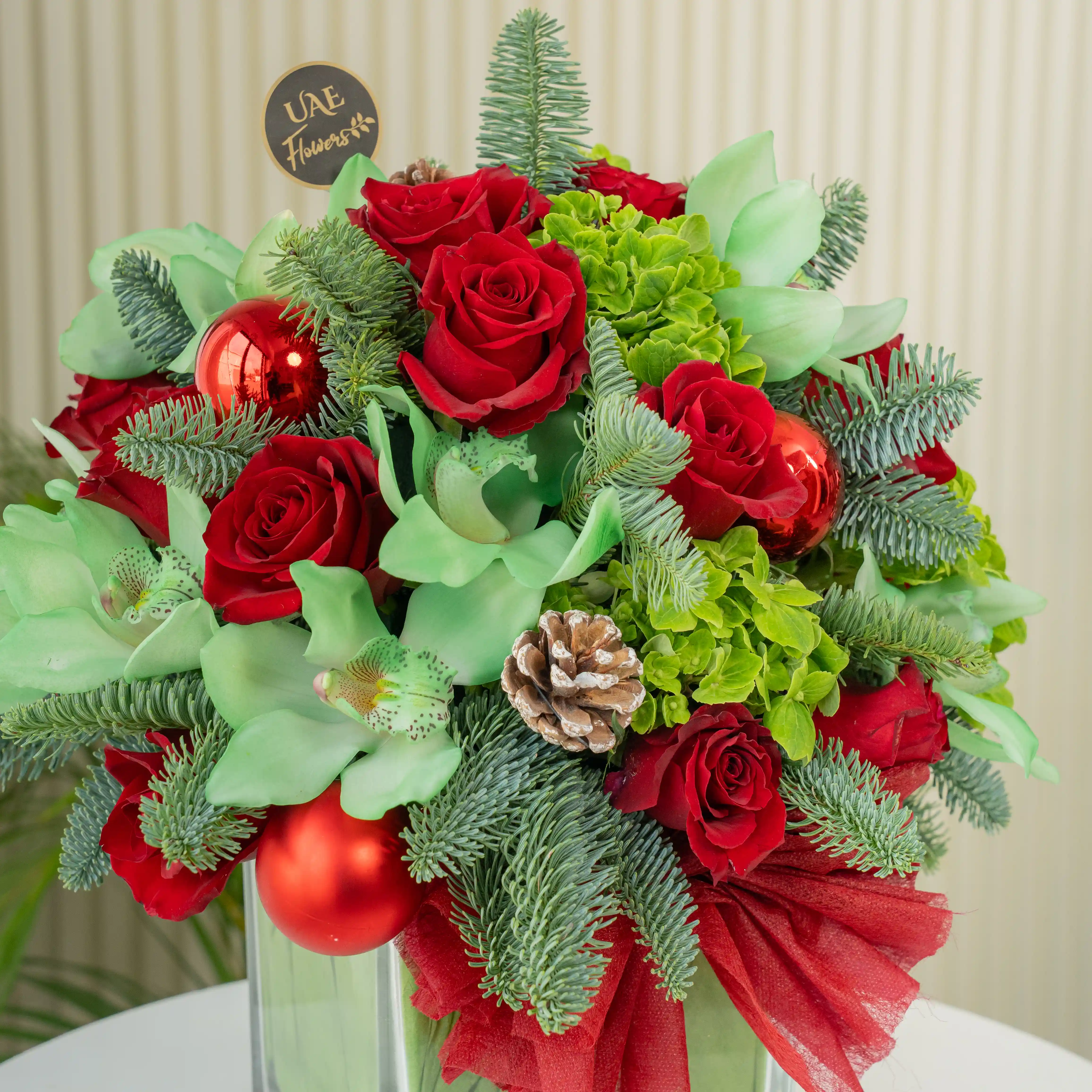 10 red roses, 1 green hydrangea, 1 green cymbidium orchid, Ornaments balls, pinecones, and fillers in a glass vase