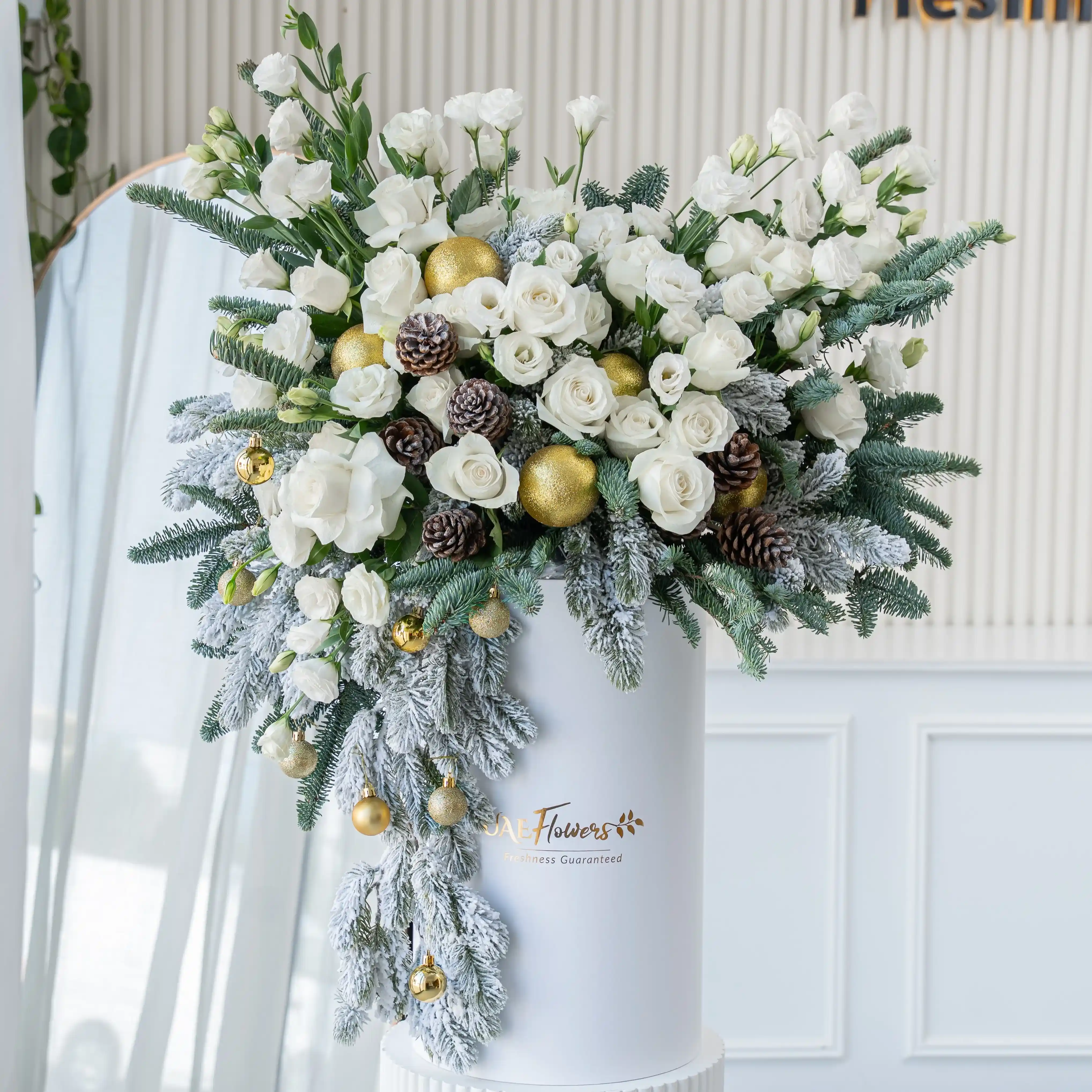 luxury white christmas flower arrangement with roses pinecones and frosted greens