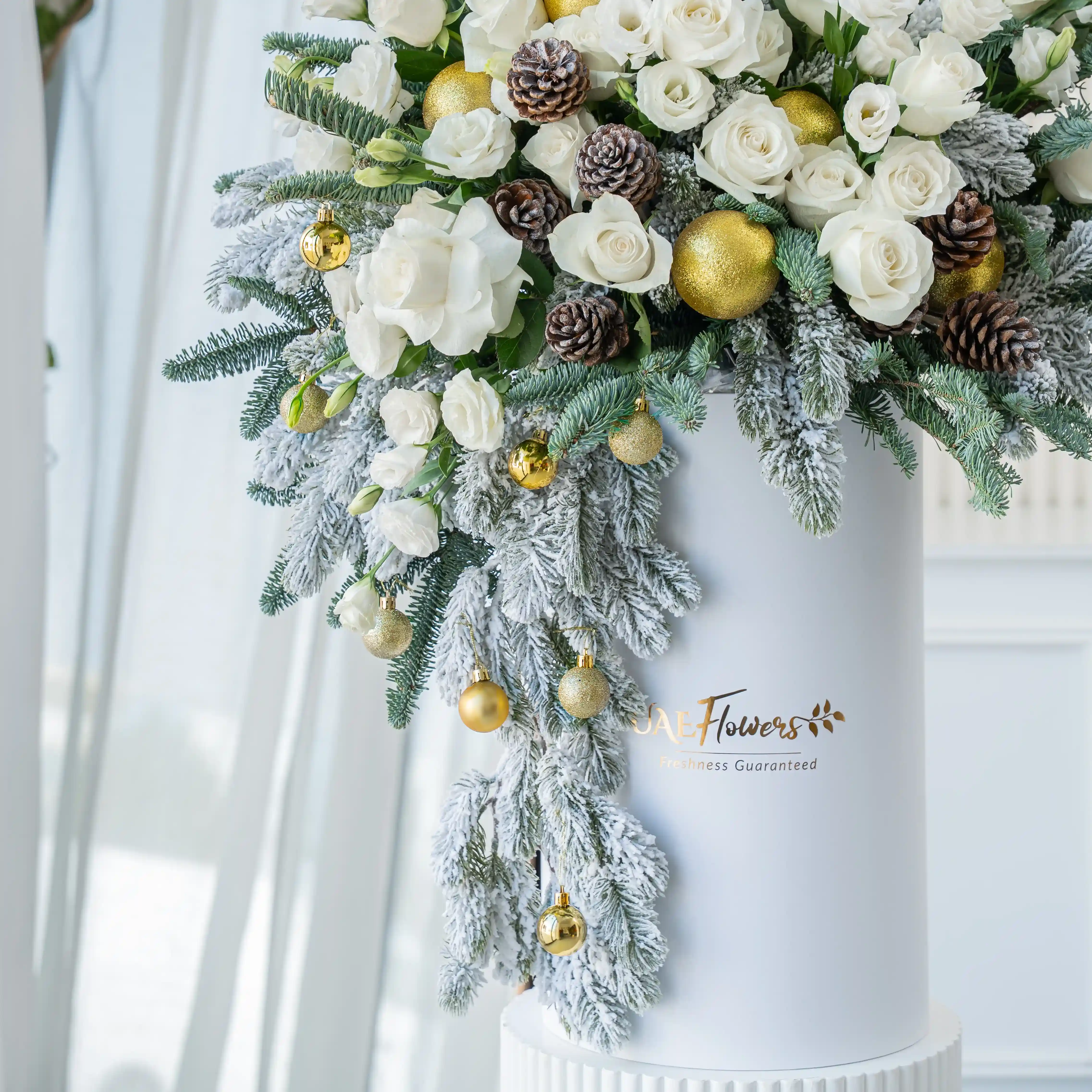 luxury white christmas flower arrangement with roses pinecones and frosted greens