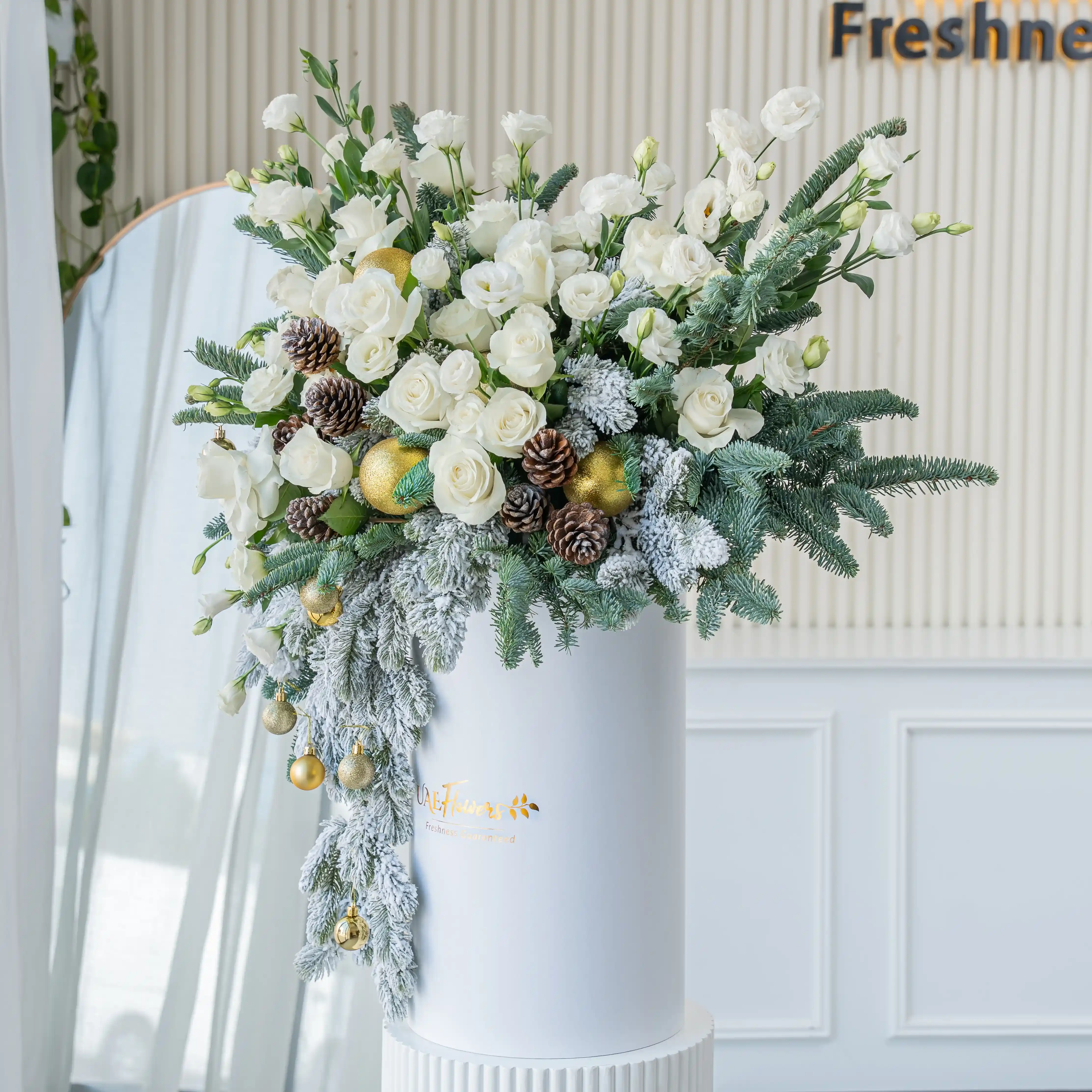 luxury white christmas flower arrangement with roses pinecones and frosted greens