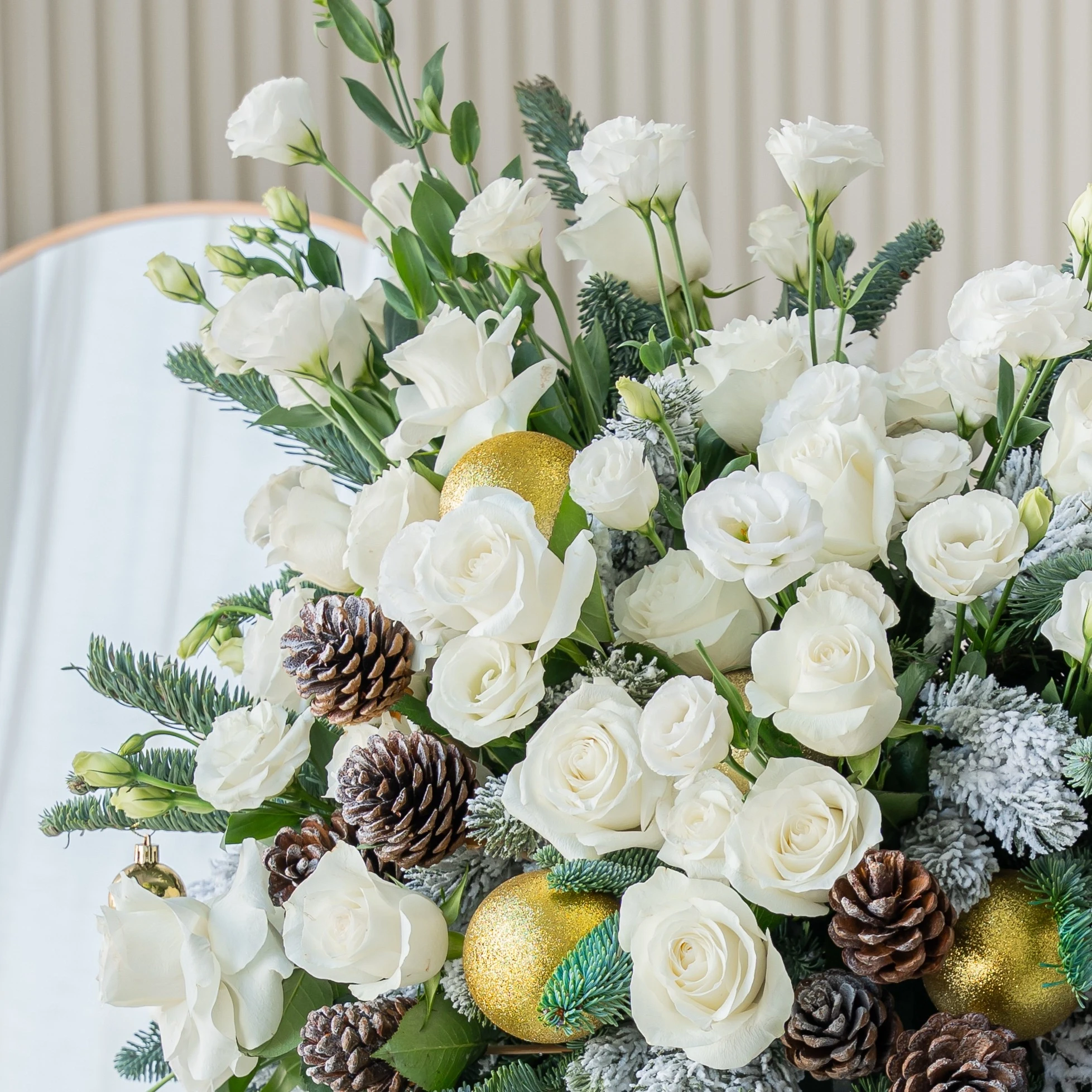 luxury white christmas flower arrangement with roses pinecones and frosted greens
