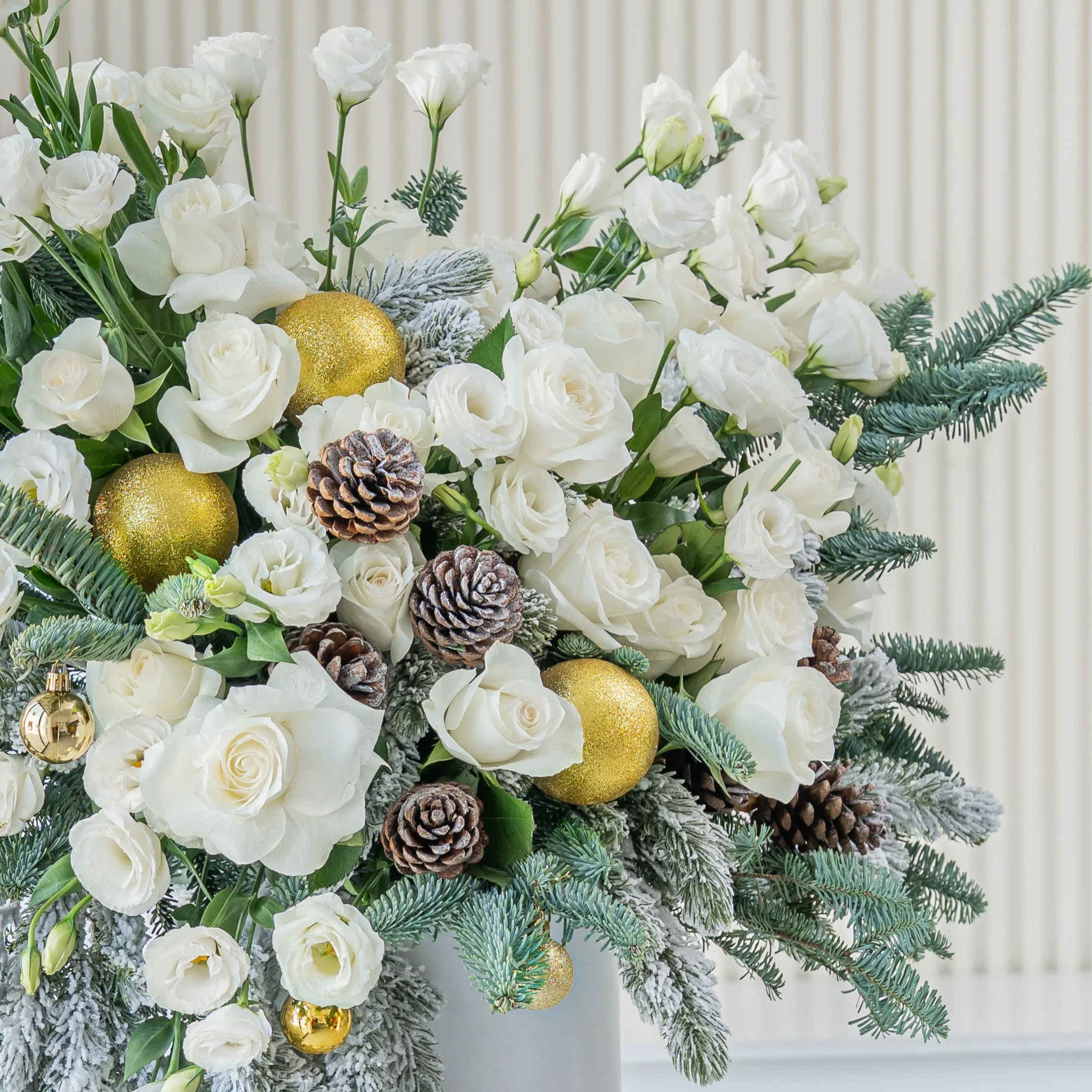 luxury white christmas flower arrangement with roses pinecones and frosted greens