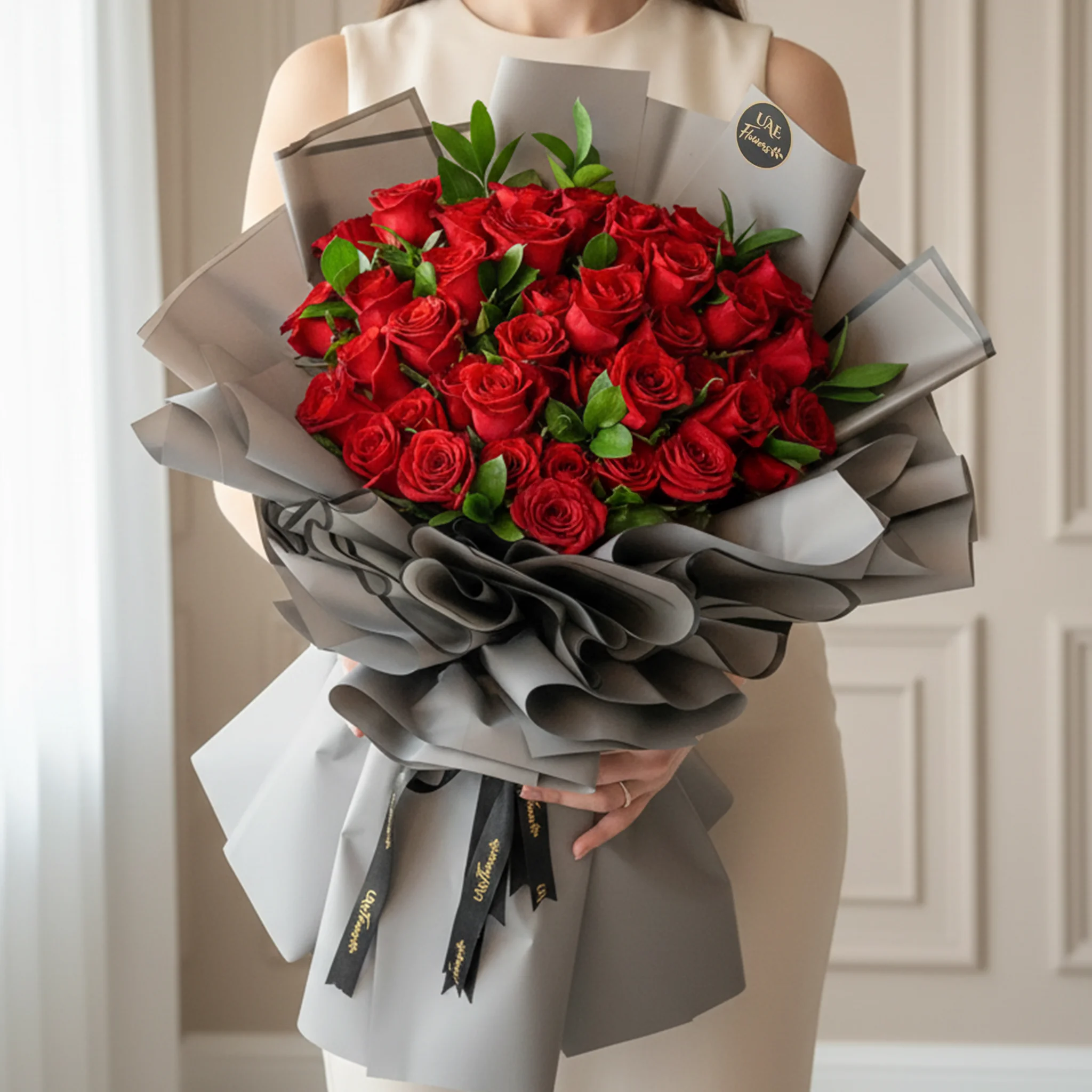 A bouquet of 40 red roses in white wrapping paper and tied with a red ribbon