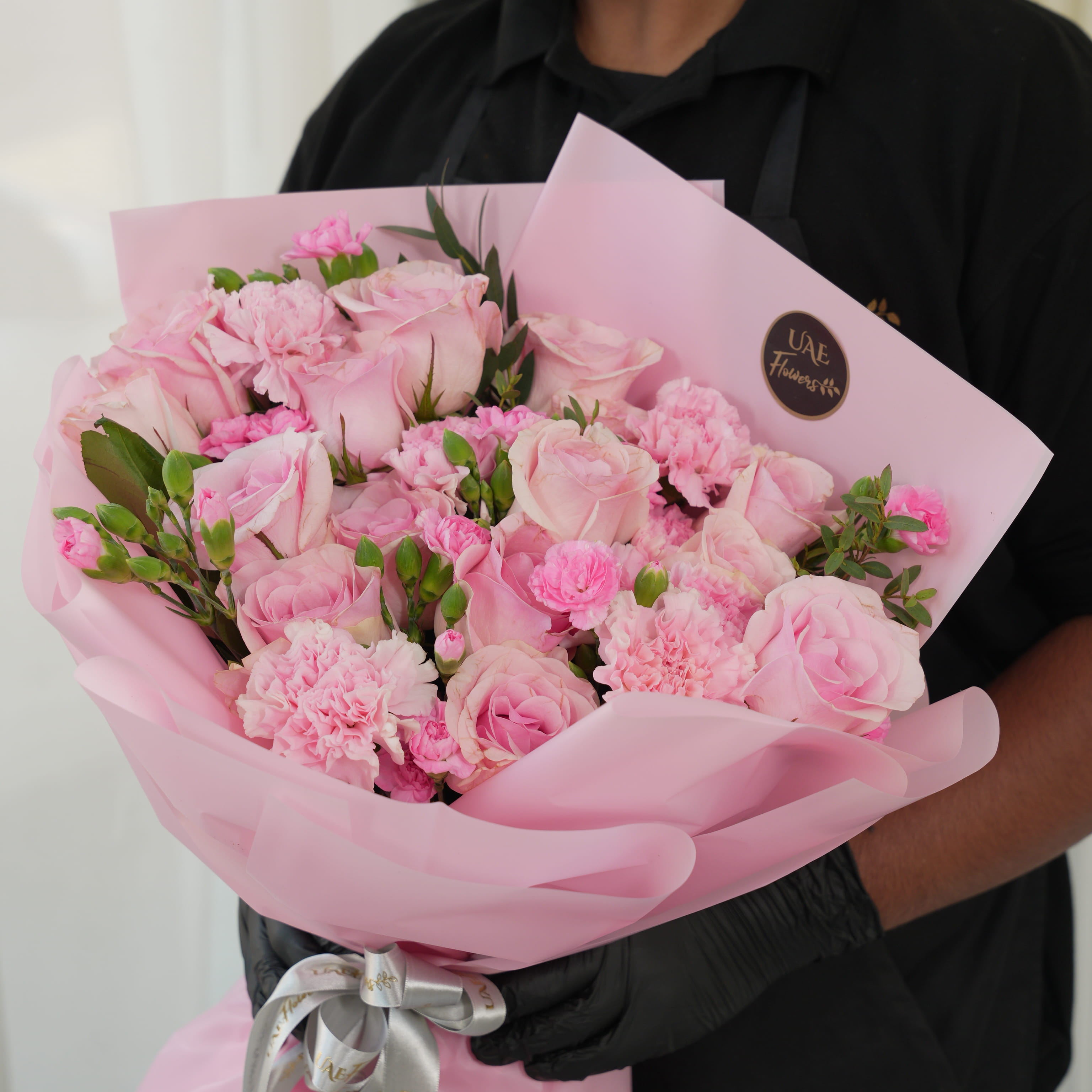 Bouquet of 15 pink roses, 5 pink carnations, 2 pink spray carnations with green fillers in pink wrapping.