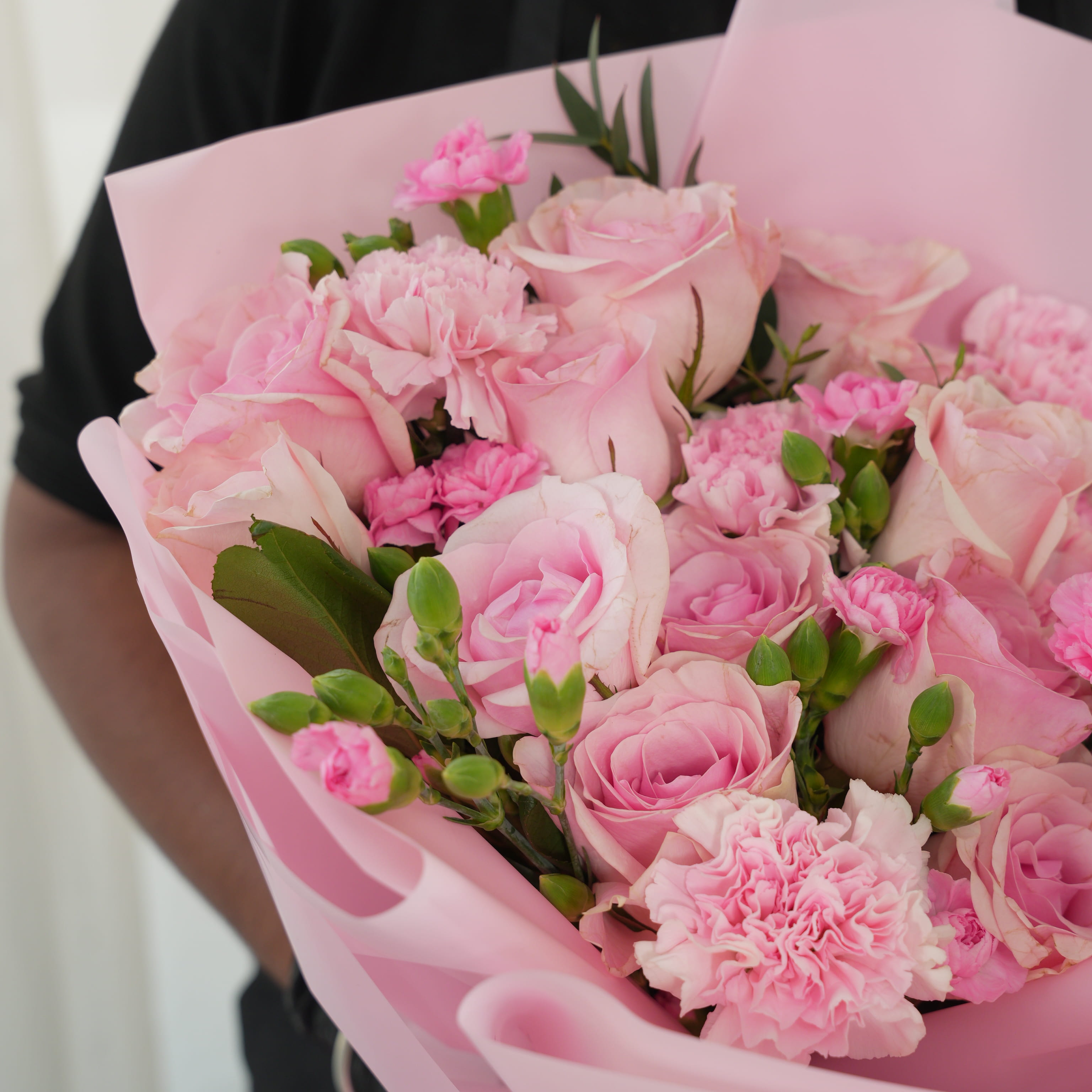 Bouquet of 15 pink roses, 5 pink carnations, 2 pink spray carnations with green fillers in pink wrapping.