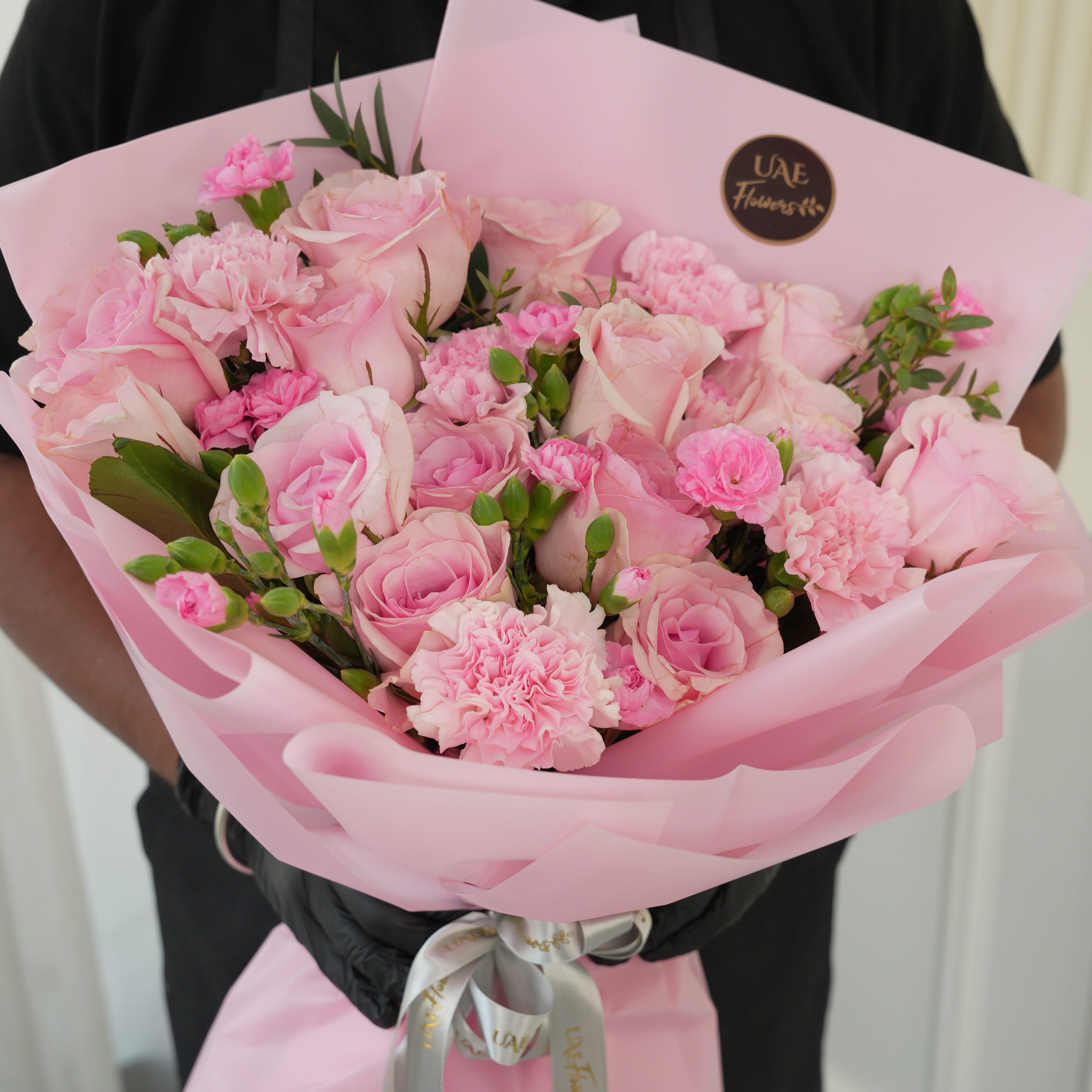 Bouquet of 15 pink roses, 5 pink carnations, 2 pink spray carnations with green fillers in pink wrapping.
