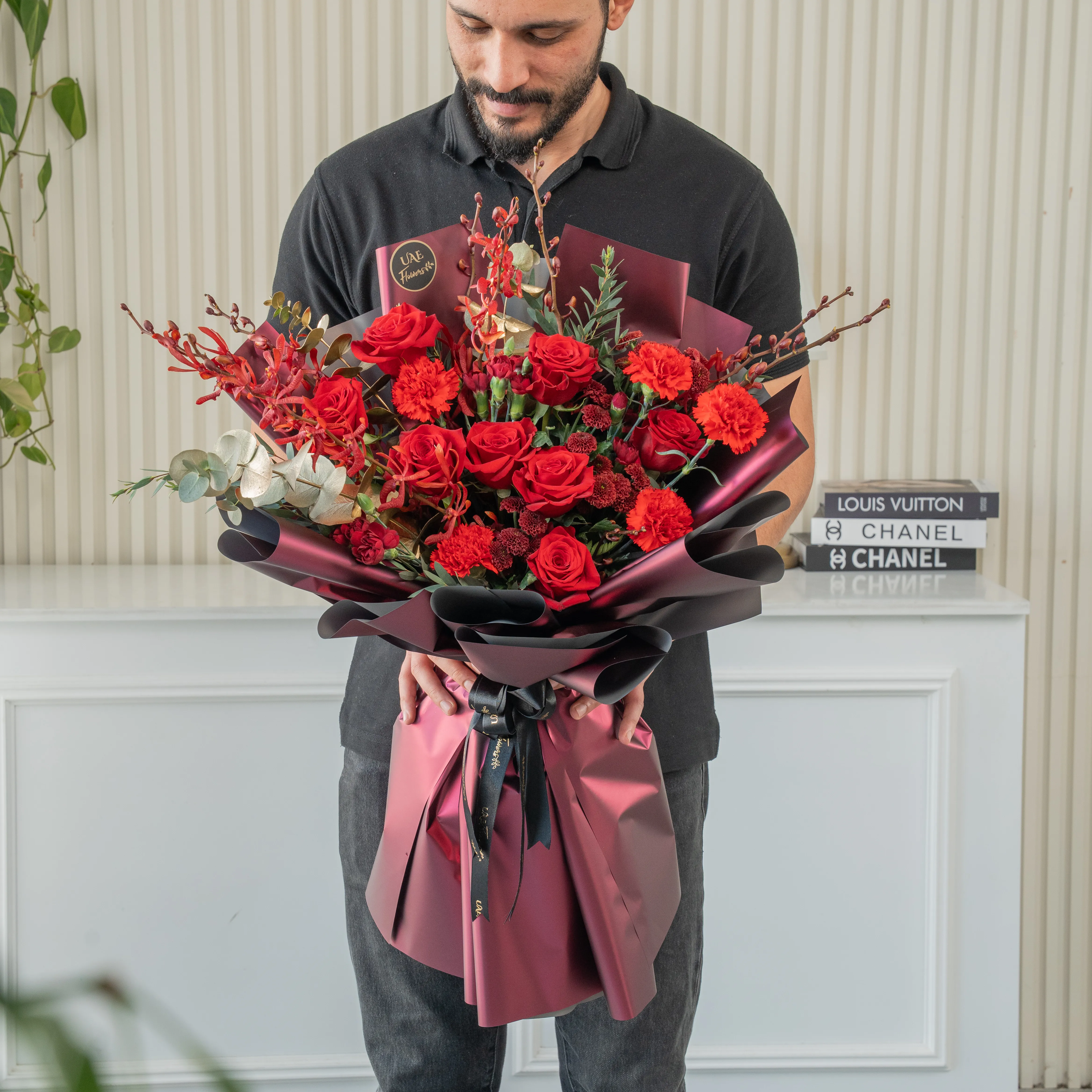 Bouquet of 7 red roses, 6 red carnations, 2 maroon button chrysanthemums with green fillers in nice paper packing.