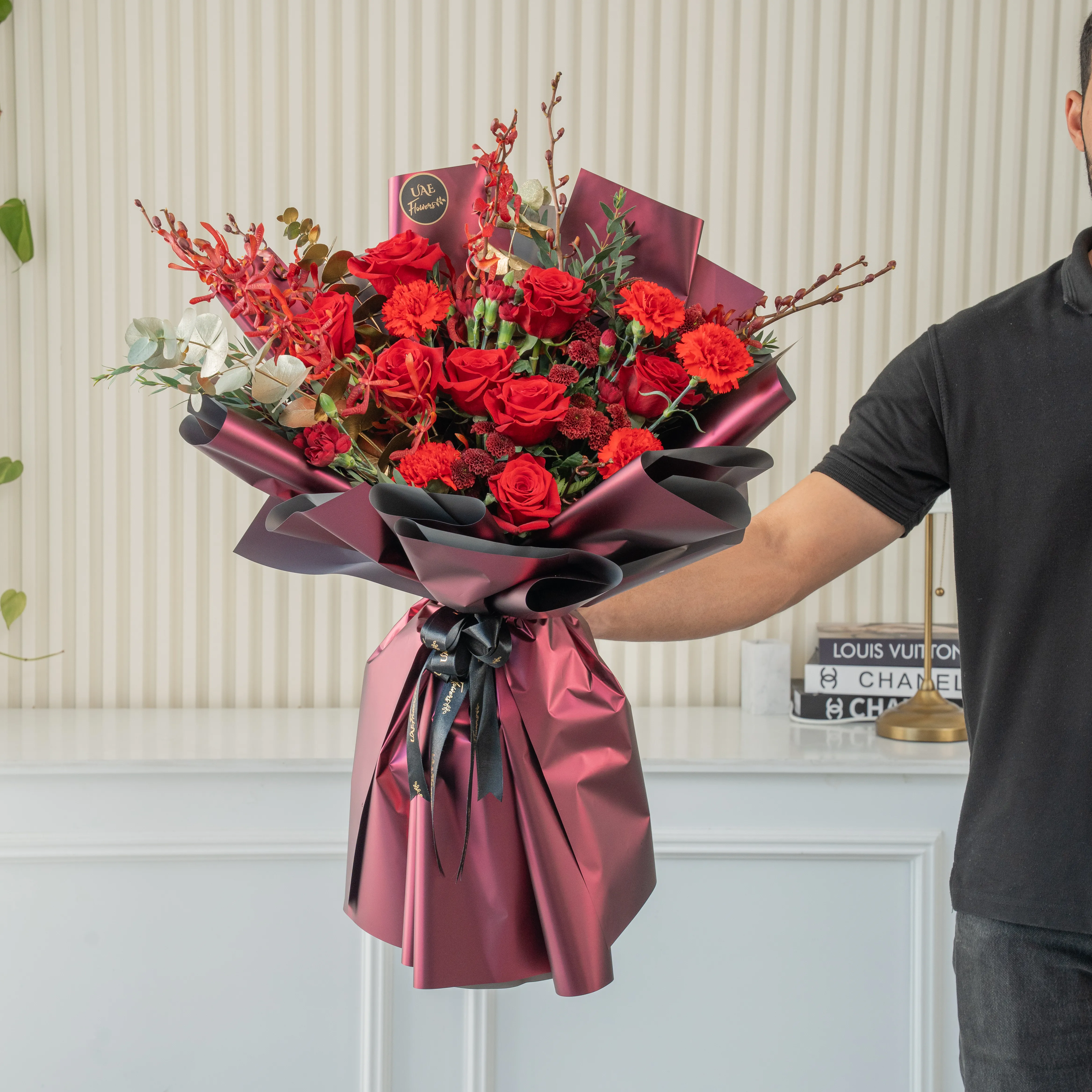 Bouquet of 7 red roses, 6 red carnations, 2 maroon button chrysanthemums with green fillers in nice paper packing.