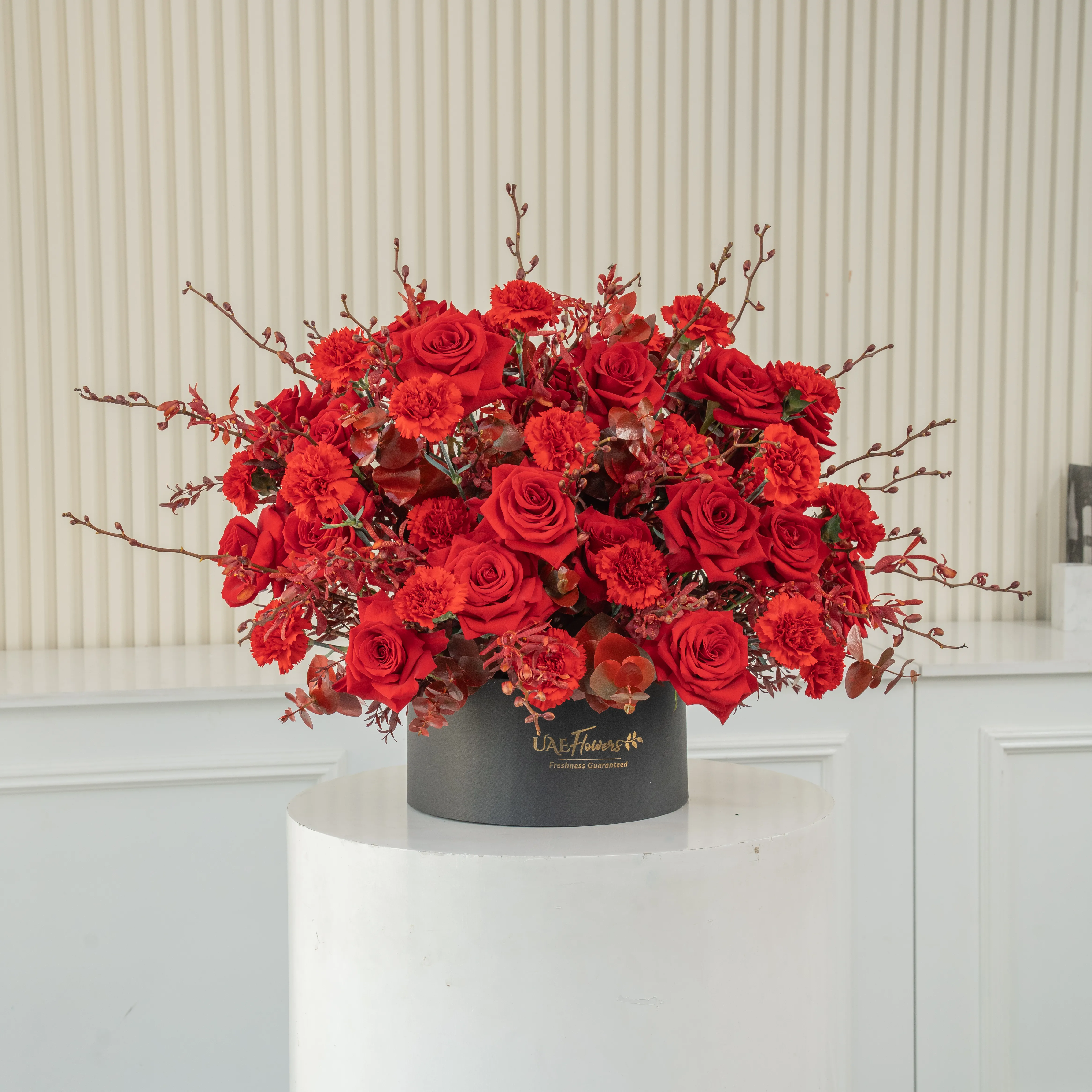 50 red roses, 25 red carnations, and 30 Annie black orchids arranged in a round box, a luxurious floral gift for grand celebrations and romantic gestures.