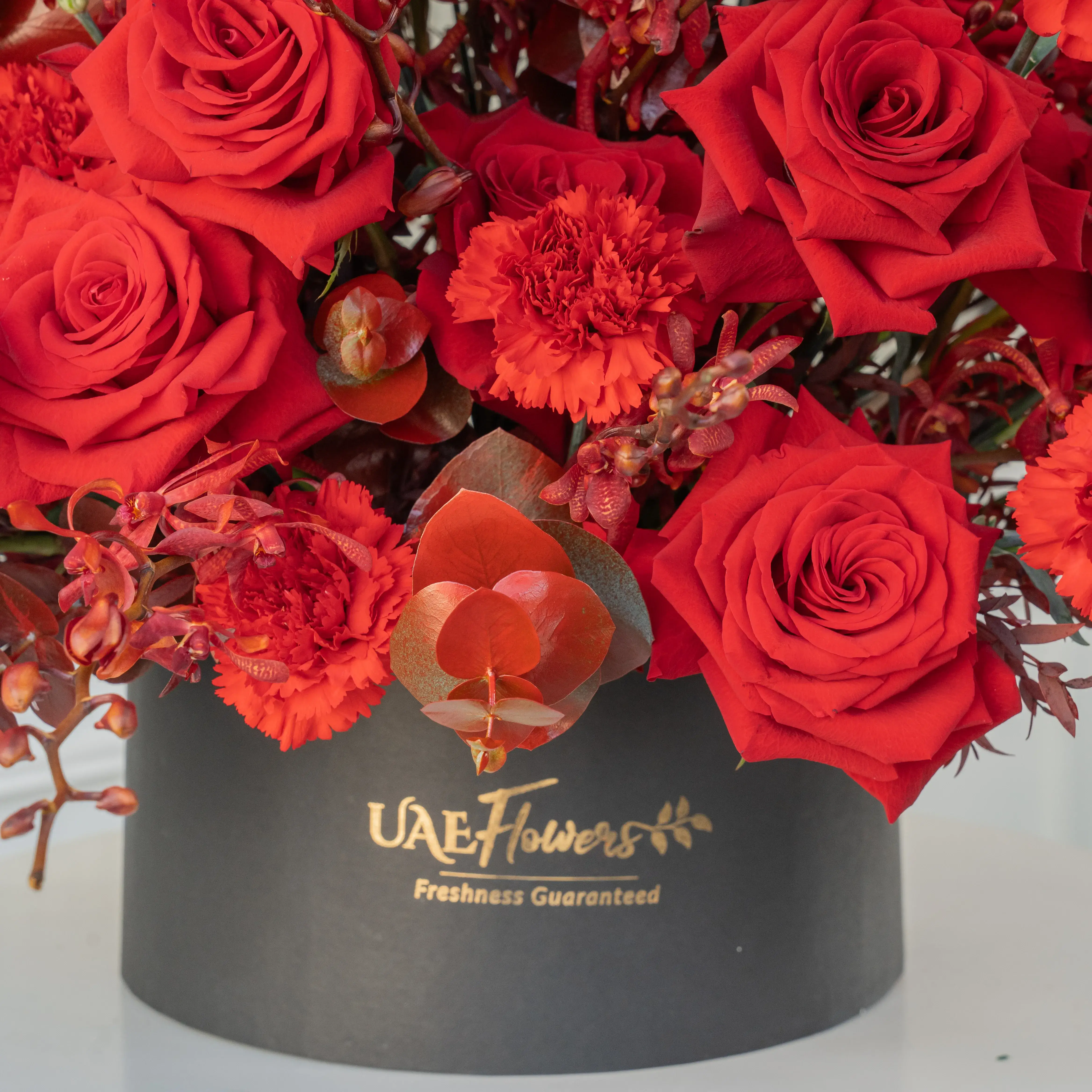 50 red roses, 25 red carnations, and 30 Annie black orchids arranged in a round box, a luxurious floral gift for grand celebrations and romantic gestures.