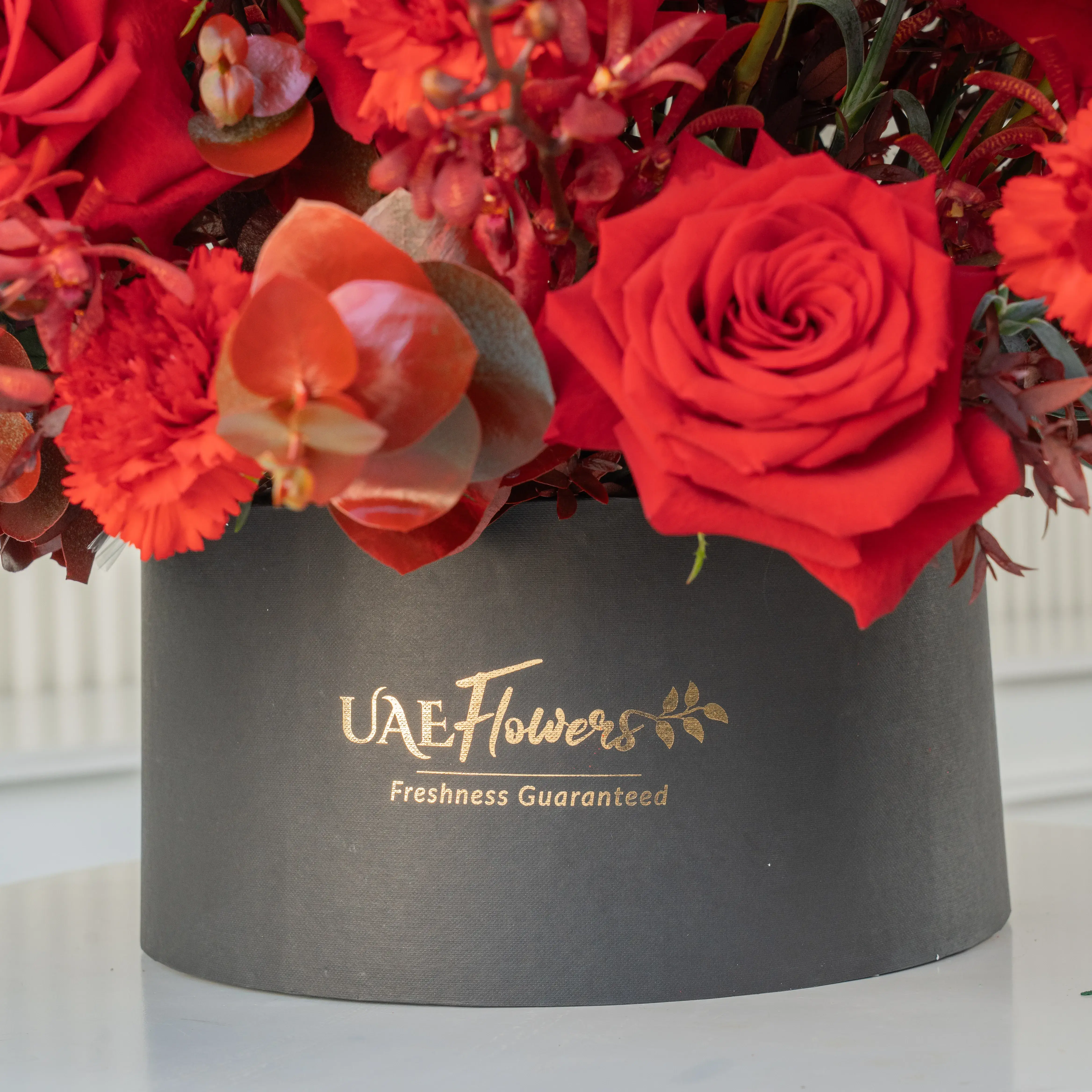 50 red roses, 25 red carnations, and 30 Annie black orchids arranged in a round box, a luxurious floral gift for grand celebrations and romantic gestures.