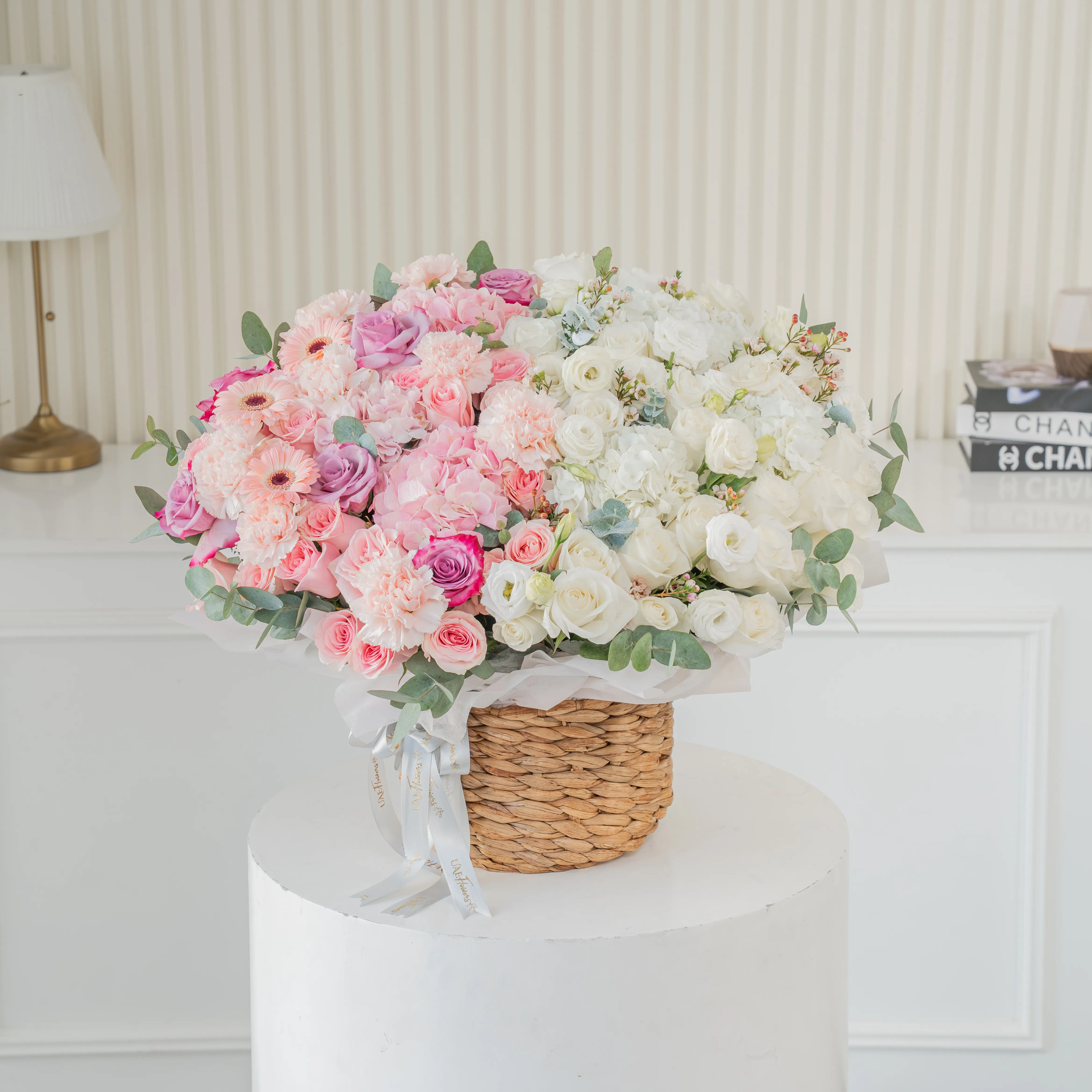 3 pink hydrangeas, 10 pink roses, 10 purple roses, 10 pink carnations, 3 pink gerberas, 3 white hydrangeas, 20 white roses and 7 white lisianthus with green fillers in a basket.