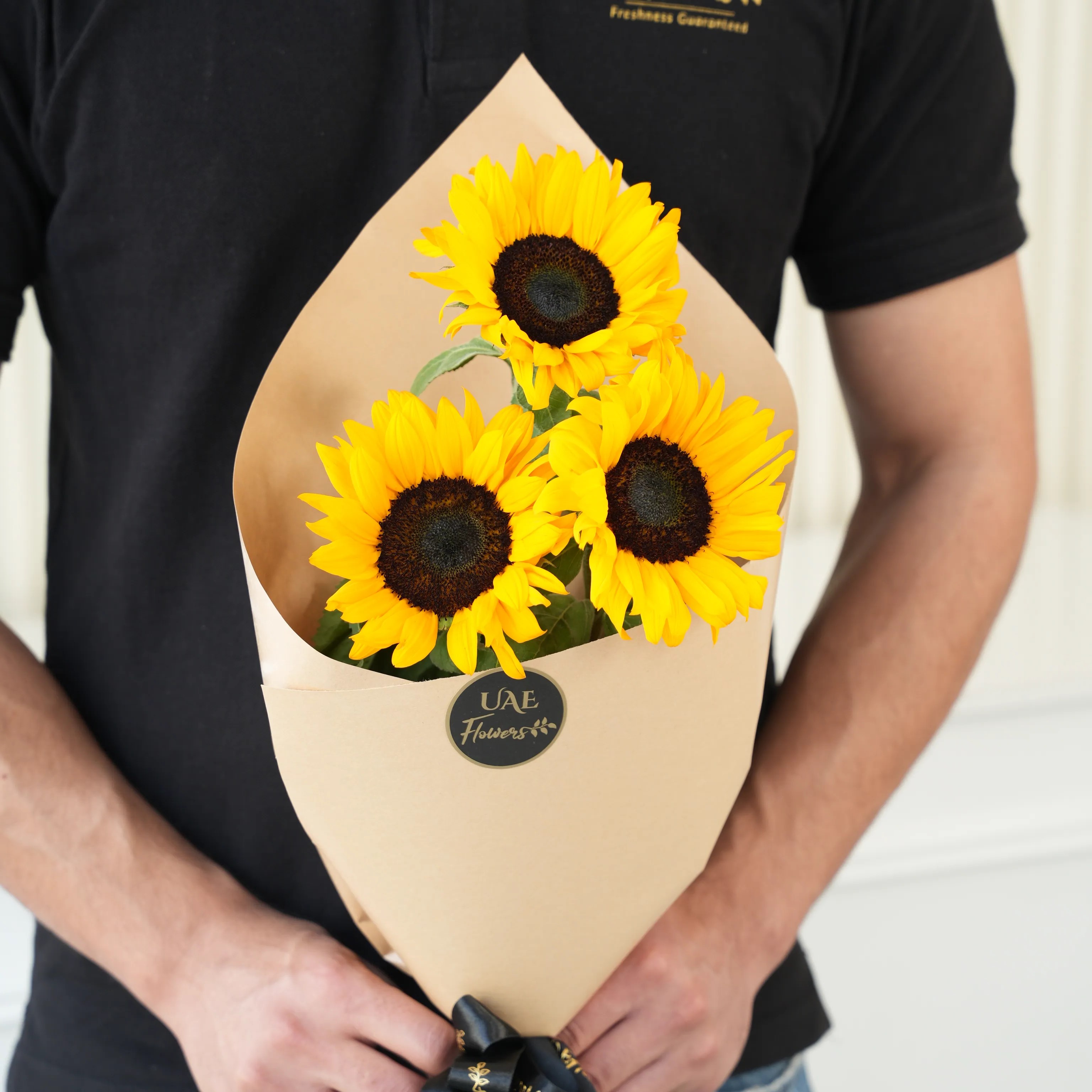 Bouquet of 3 sunflowers in paper packing hand-tied with ribbons.