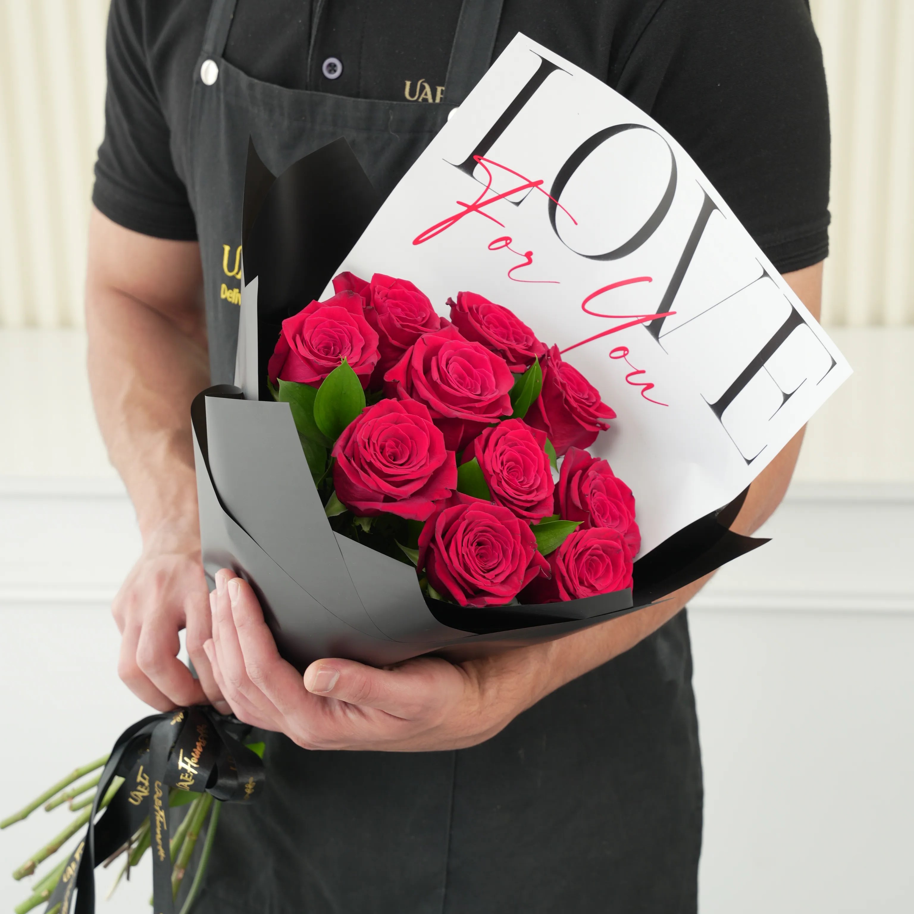 10 red roses with green fillers in black wrapping with Love For You Paper tied with black ribbons.