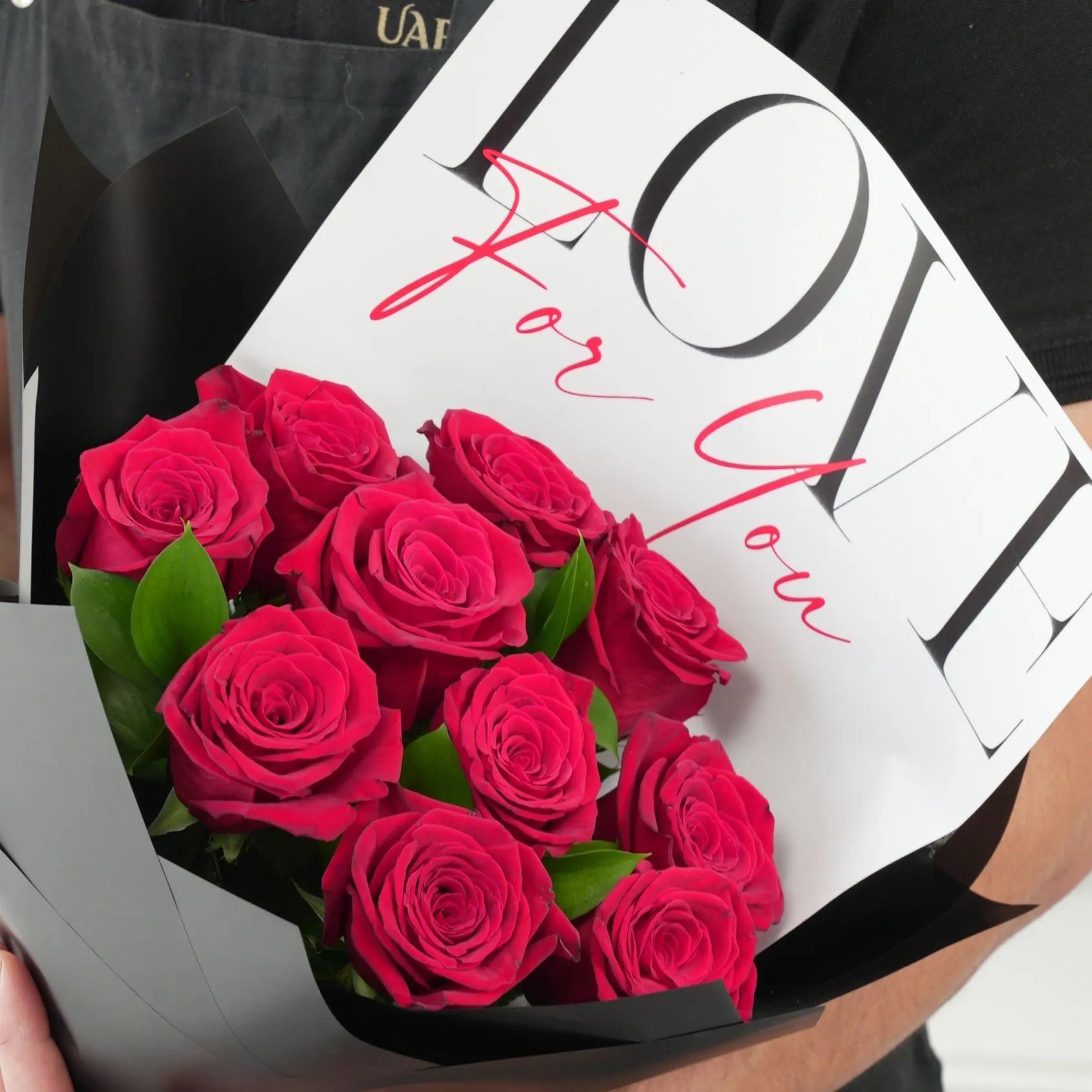 10 red roses with green fillers in black wrapping with Love For You Paper tied with black ribbons.