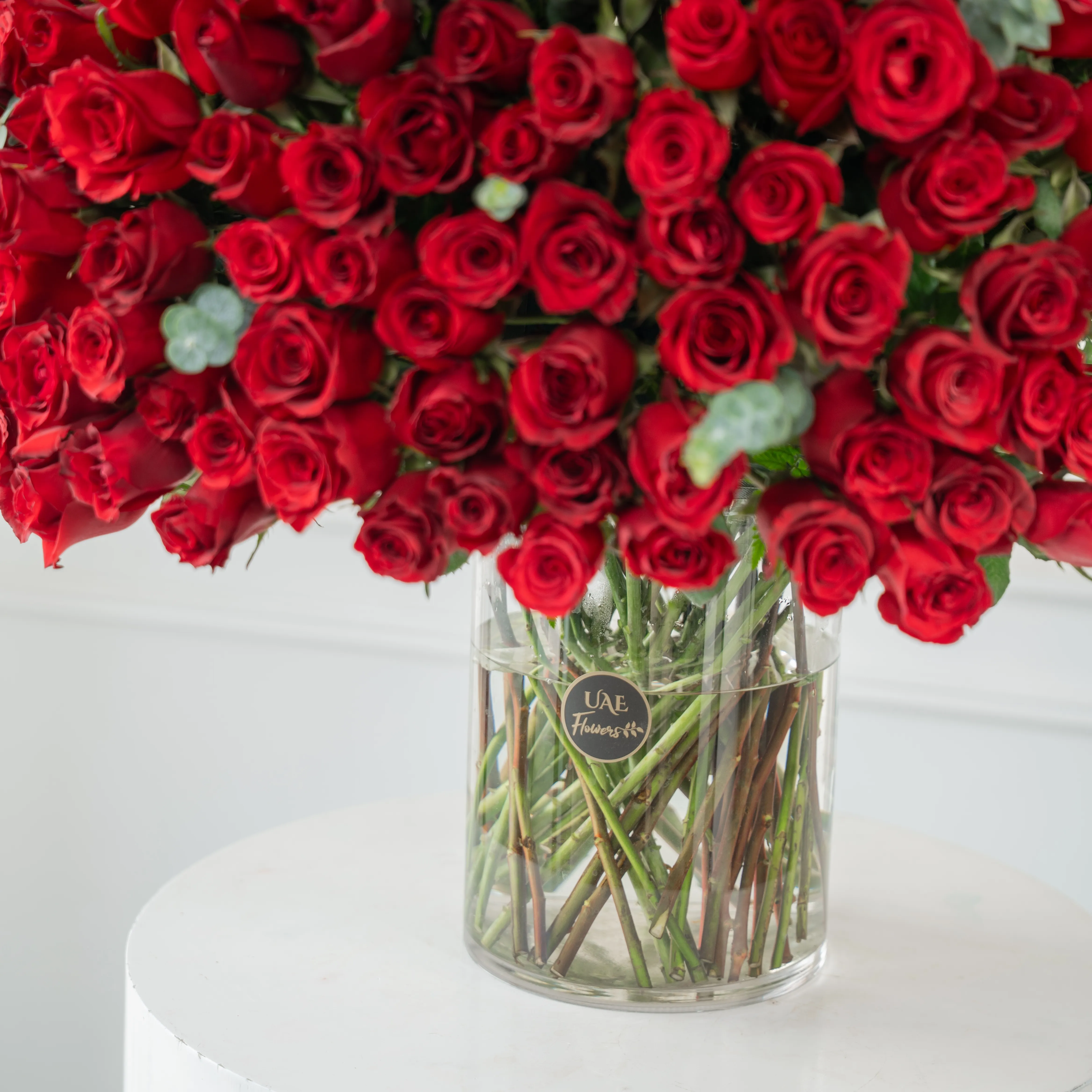 200 red roses with green fillers in a glass vase.
