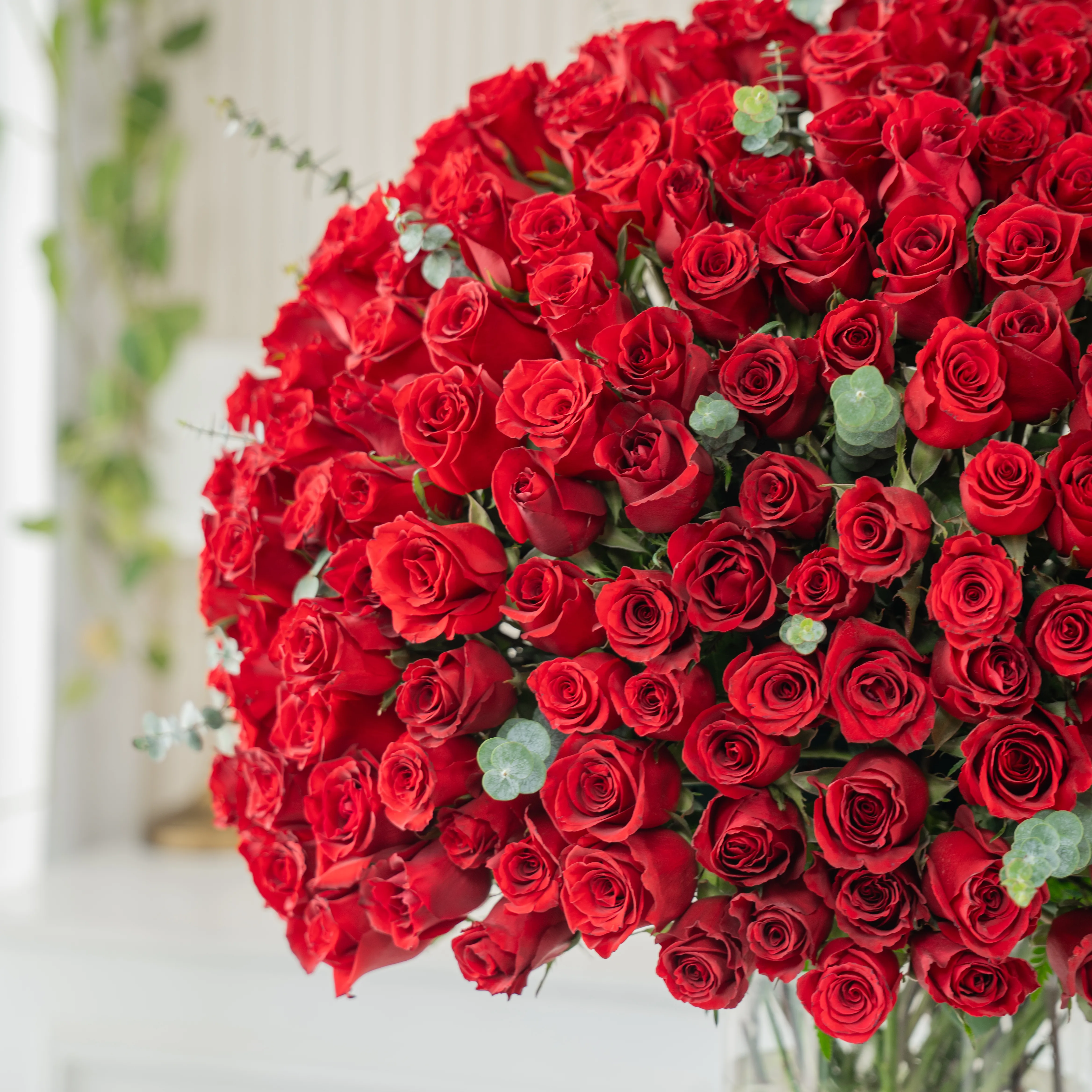 200 red roses with green fillers in a glass vase.