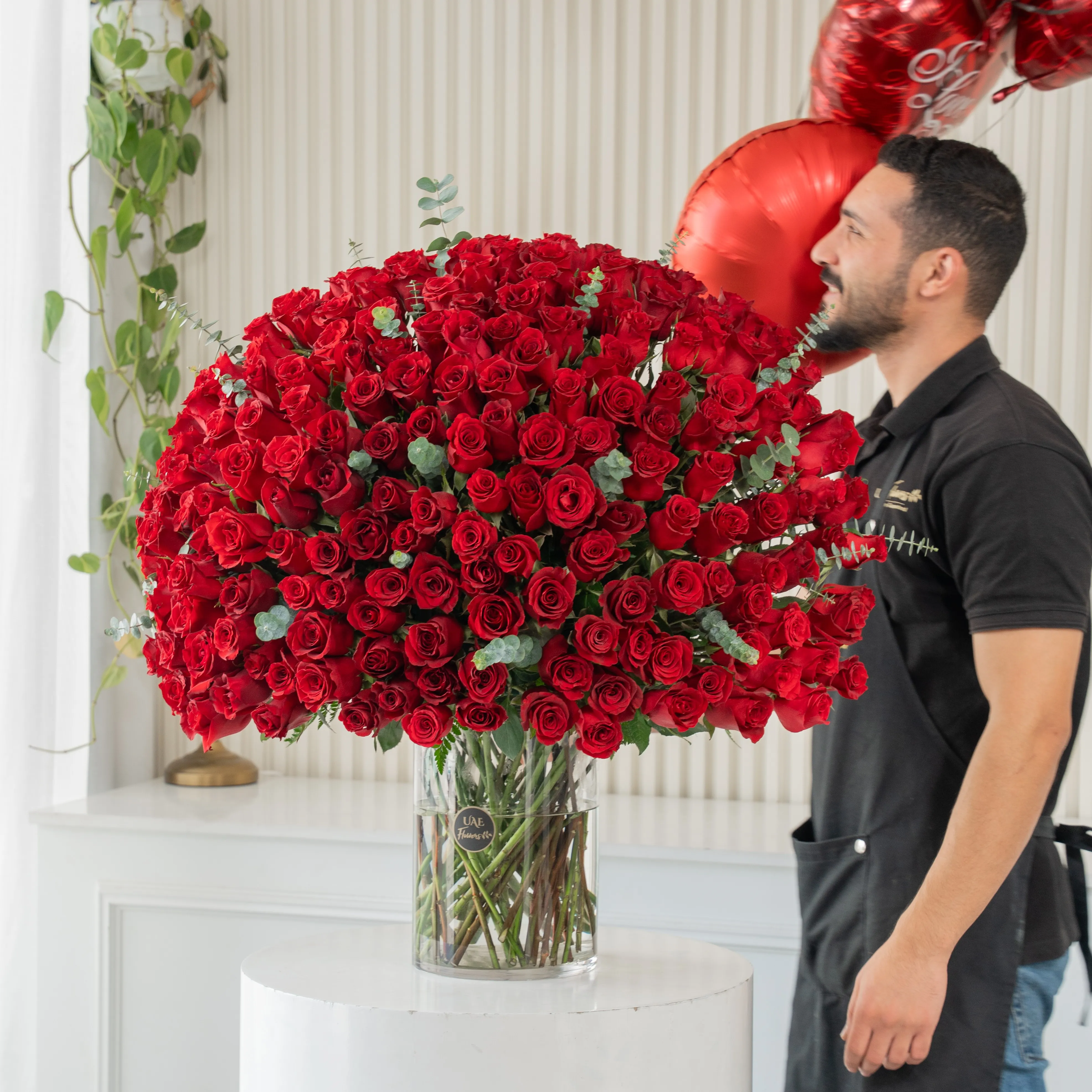 200 red roses with green fillers in a glass vase.