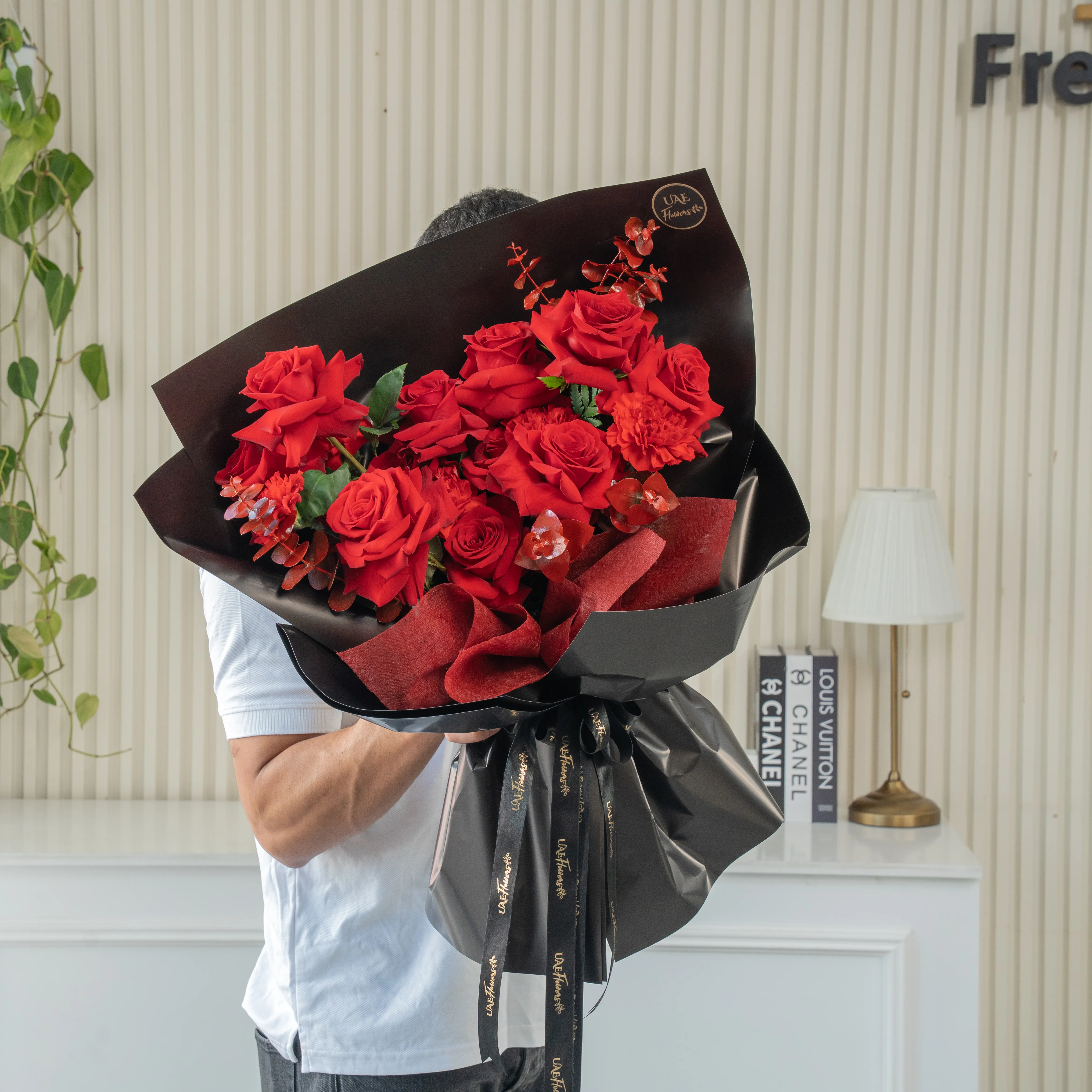 Bouquet of 8 red roses, 2 red spray roses, red alstroemeria with eucalyptus leaf in black paper packing.