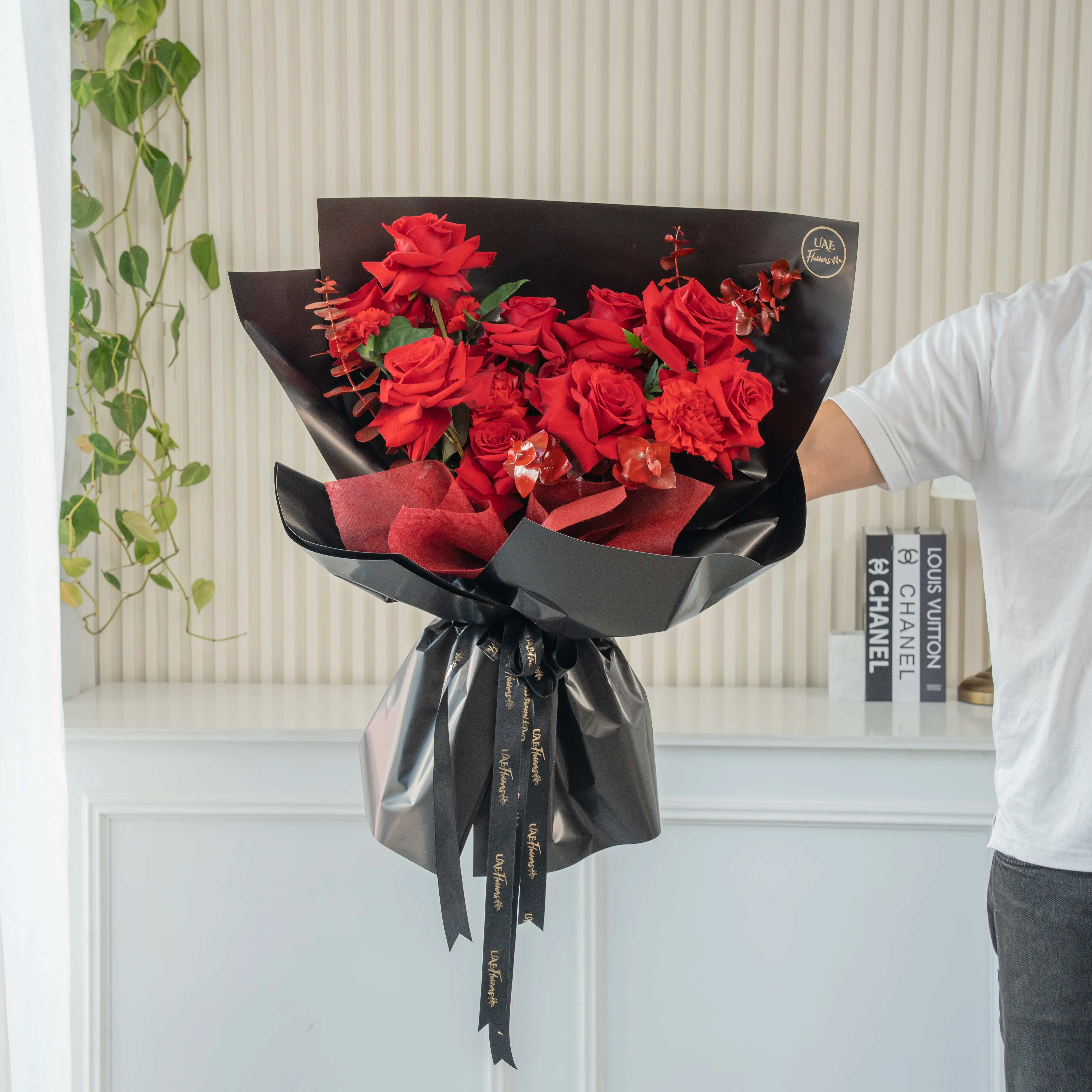 Bouquet of 8 red roses, 2 red spray roses, red alstroemeria with eucalyptus leaf in black paper packing.