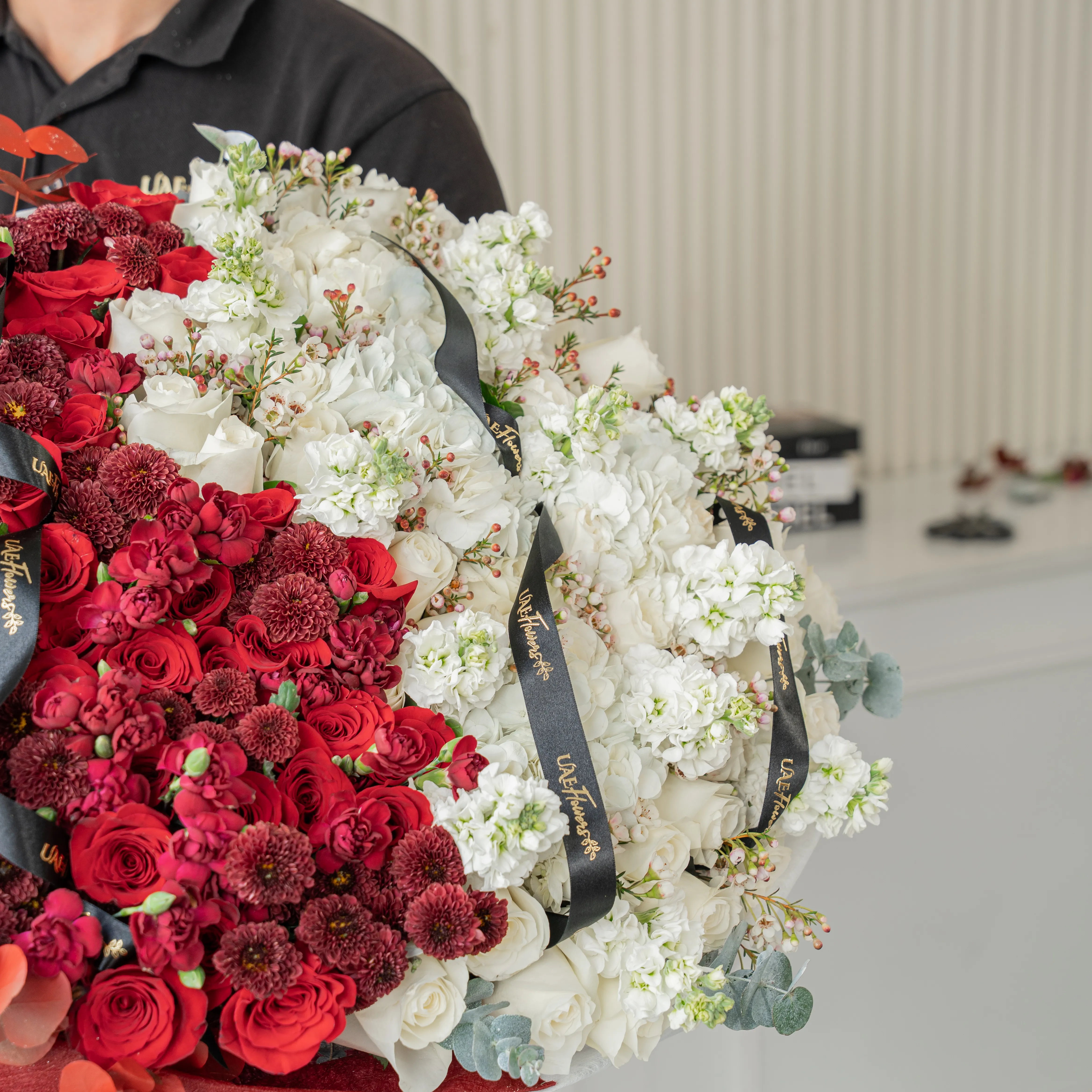 Bouquet of 25 red roses, 15 red chrysanthemums, 10 red spray carnations, 3 white hydrangeas, 25 white roses and 10 white matthiola with eucalyptus leaf in red and white wrapping paper tied with ribbon.