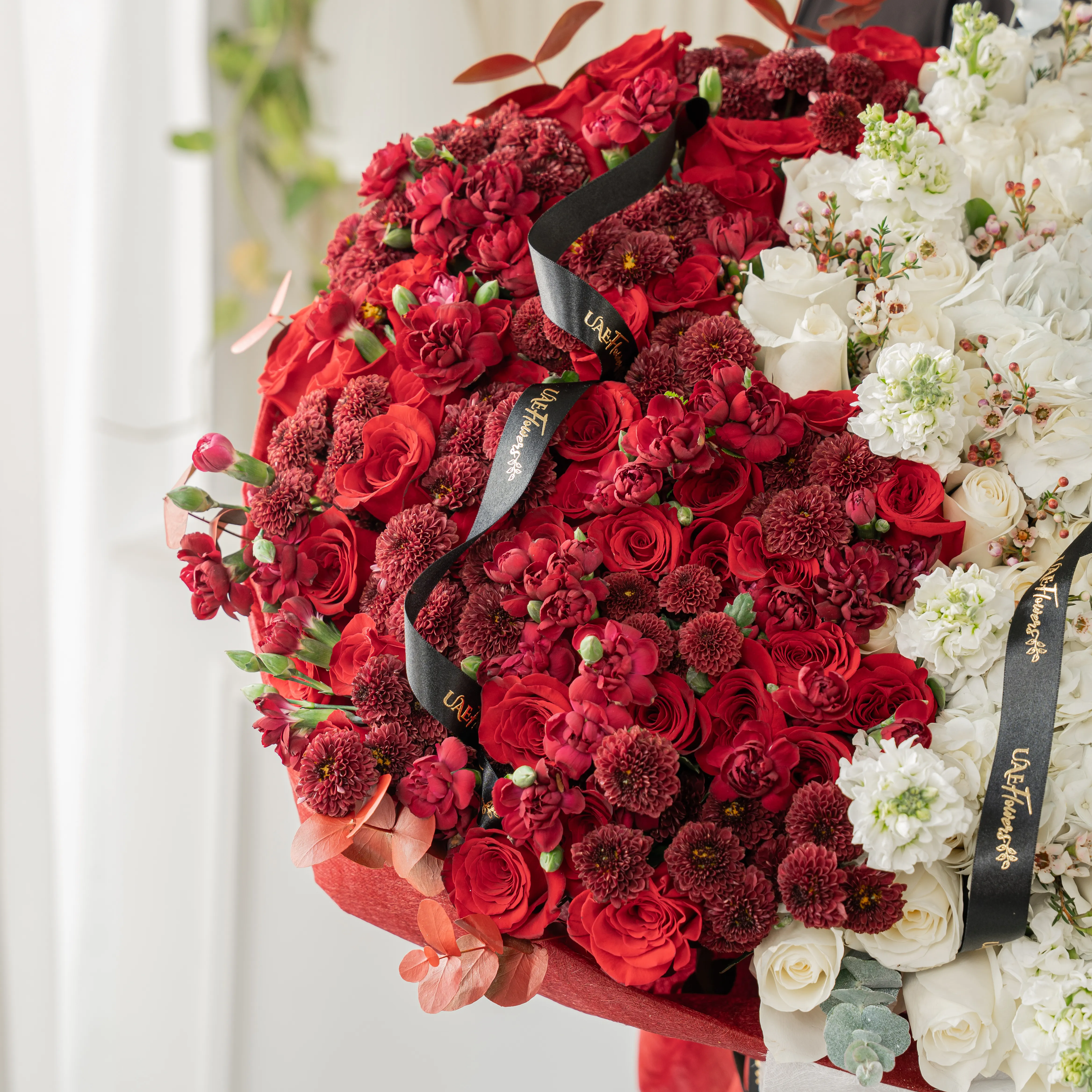 Bouquet of 25 red roses, 15 red chrysanthemums, 10 red spray carnations, 3 white hydrangeas, 25 white roses and 10 white matthiola with eucalyptus leaf in red and white wrapping paper tied with ribbon.