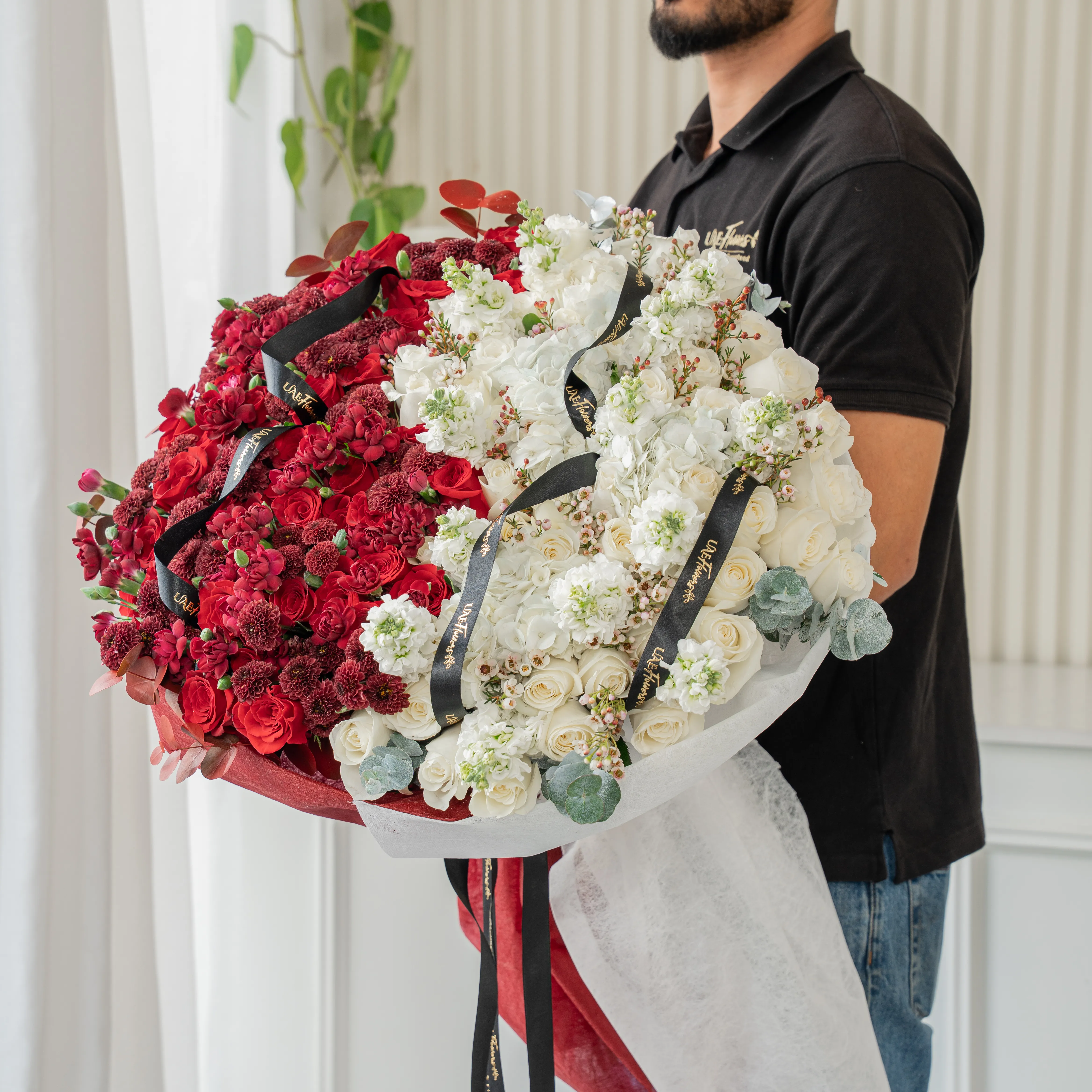 Bouquet of 25 red roses, 15 red chrysanthemums, 10 red spray carnations, 3 white hydrangeas, 25 white roses and 10 white matthiola with eucalyptus leaf in red and white wrapping paper tied with ribbon.