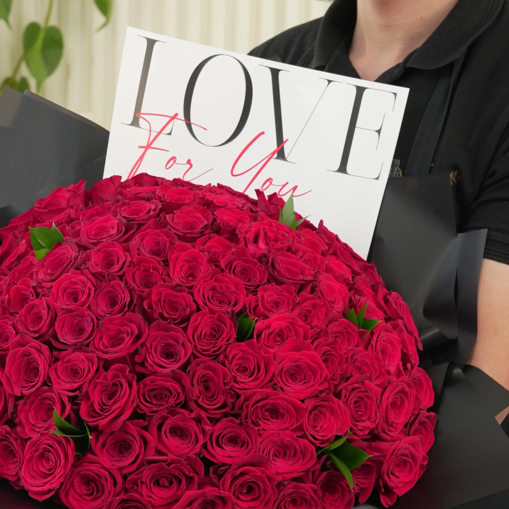 100 red roses with green fillers in black wrapping with Love For You Paper tied with black ribbons.