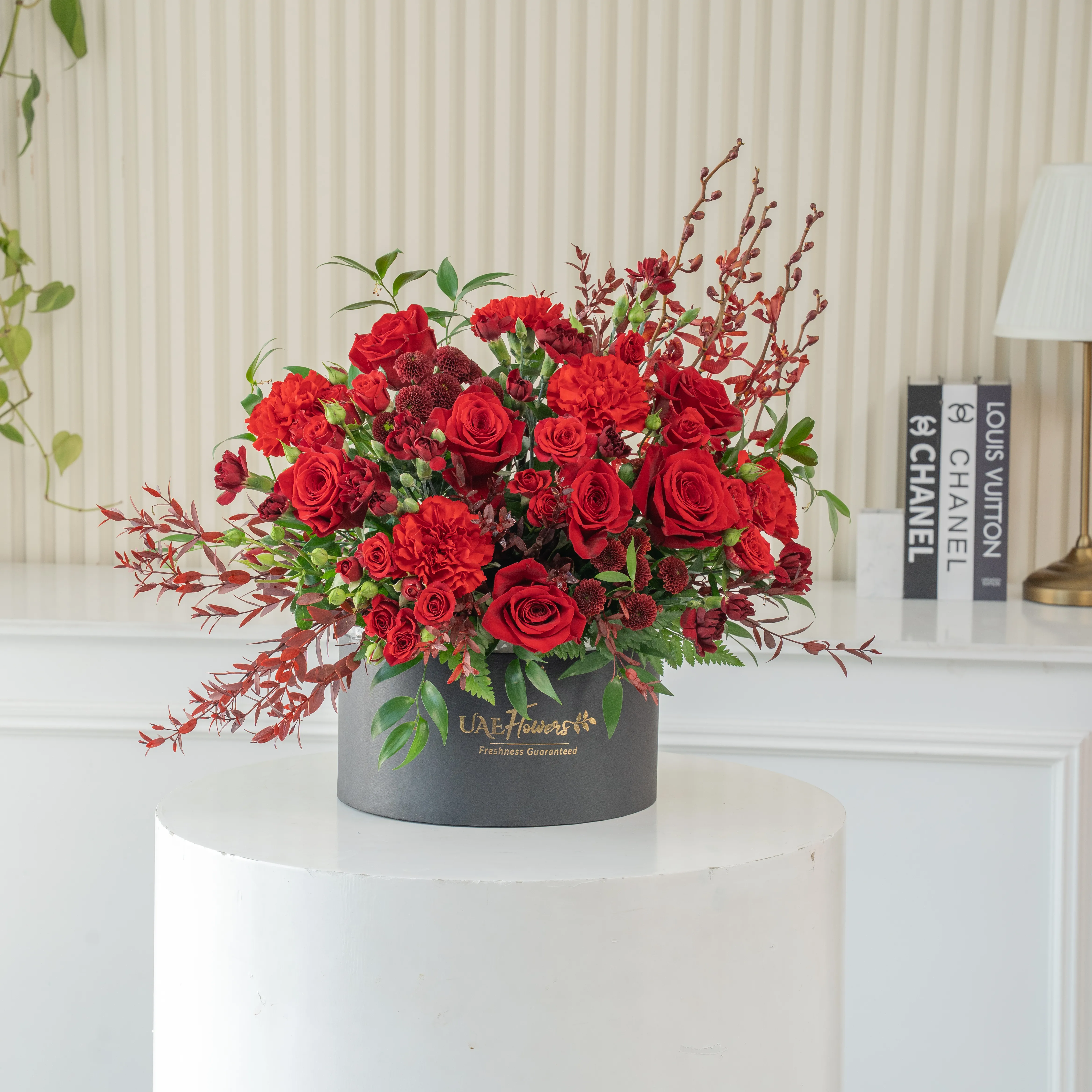 4 annie black orchids, 8 red roses, 3 red spray roses, 2 red chrysanthemums and 4 red spray carnations with green fillers in a round box.