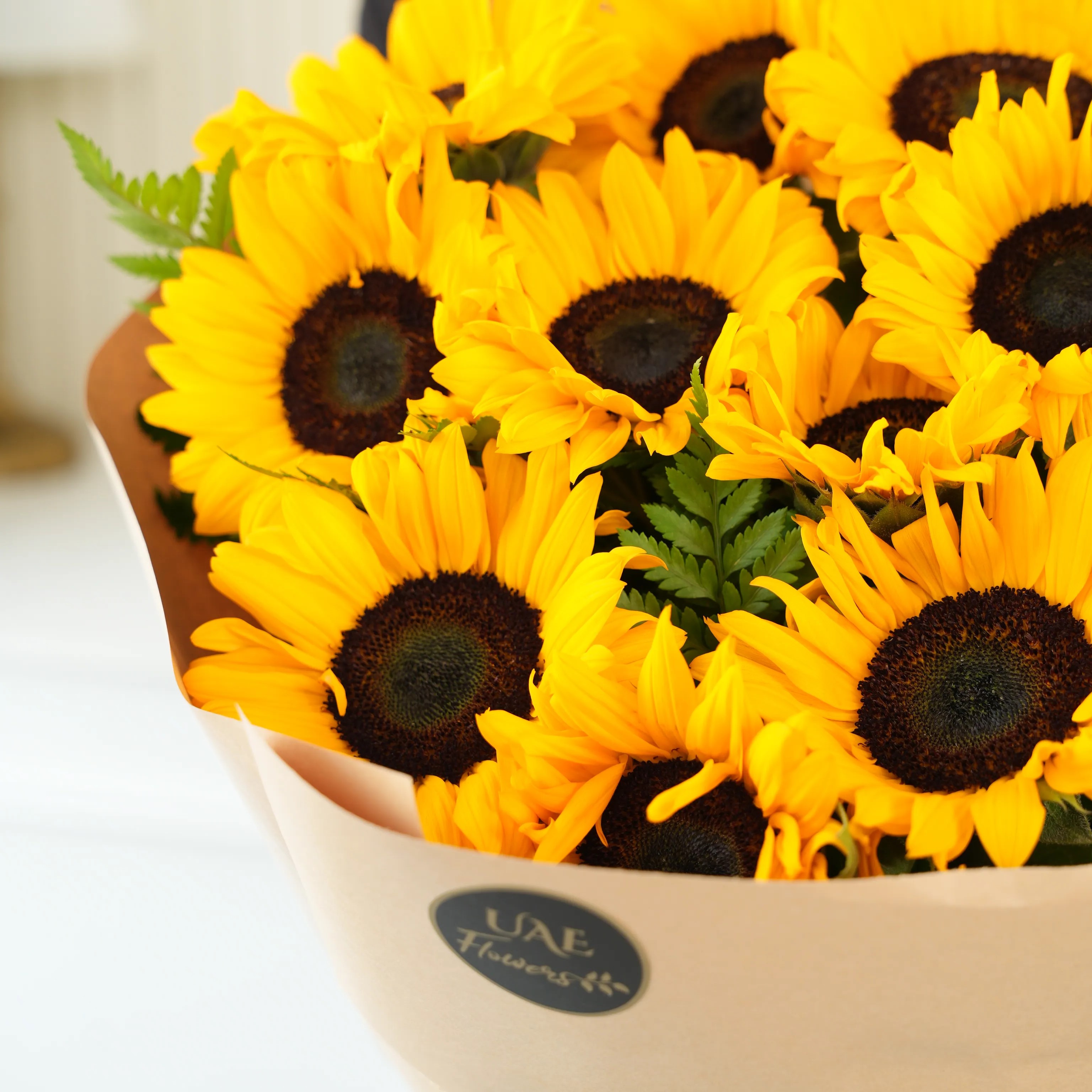 Bouquet of 12 sunflowers in paper packing hand-tied with ribbons.