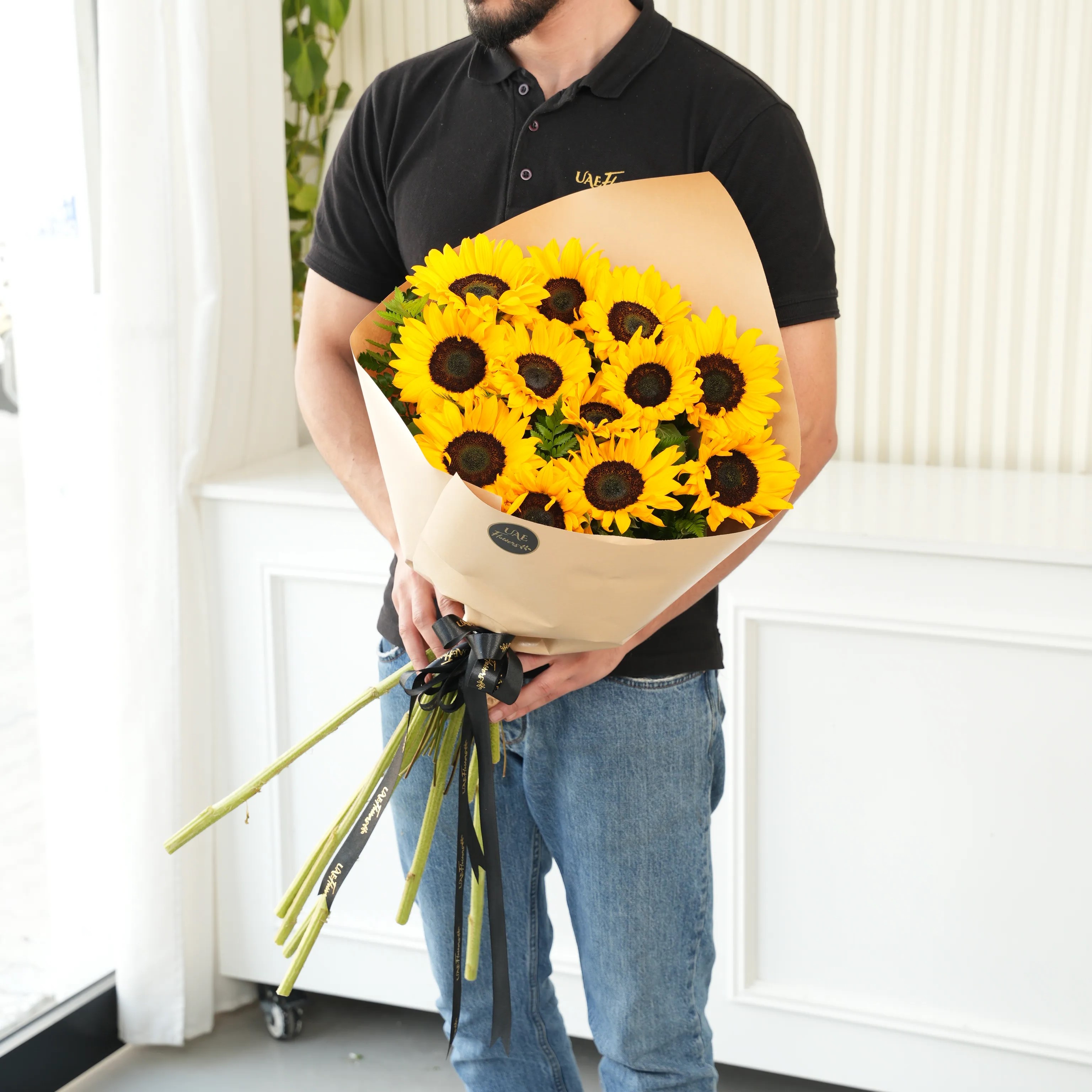 Bouquet of 12 sunflowers in paper packing hand-tied with ribbons.