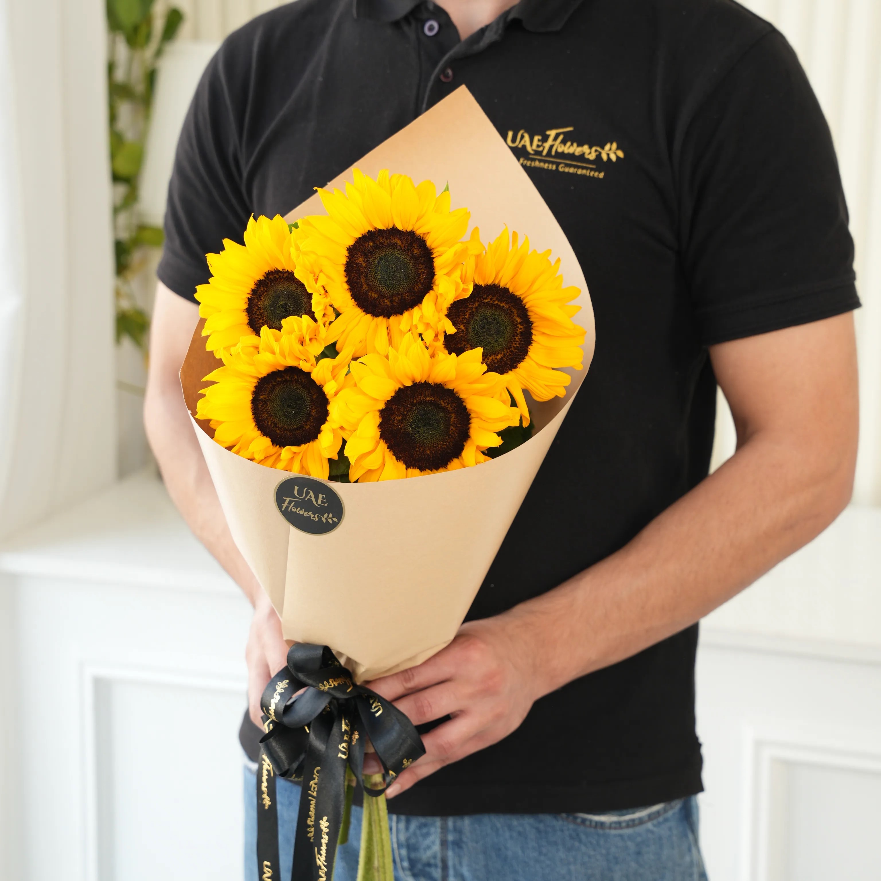 Bouquet of 5 sunflowers in paper packing hand-tied with ribbons.