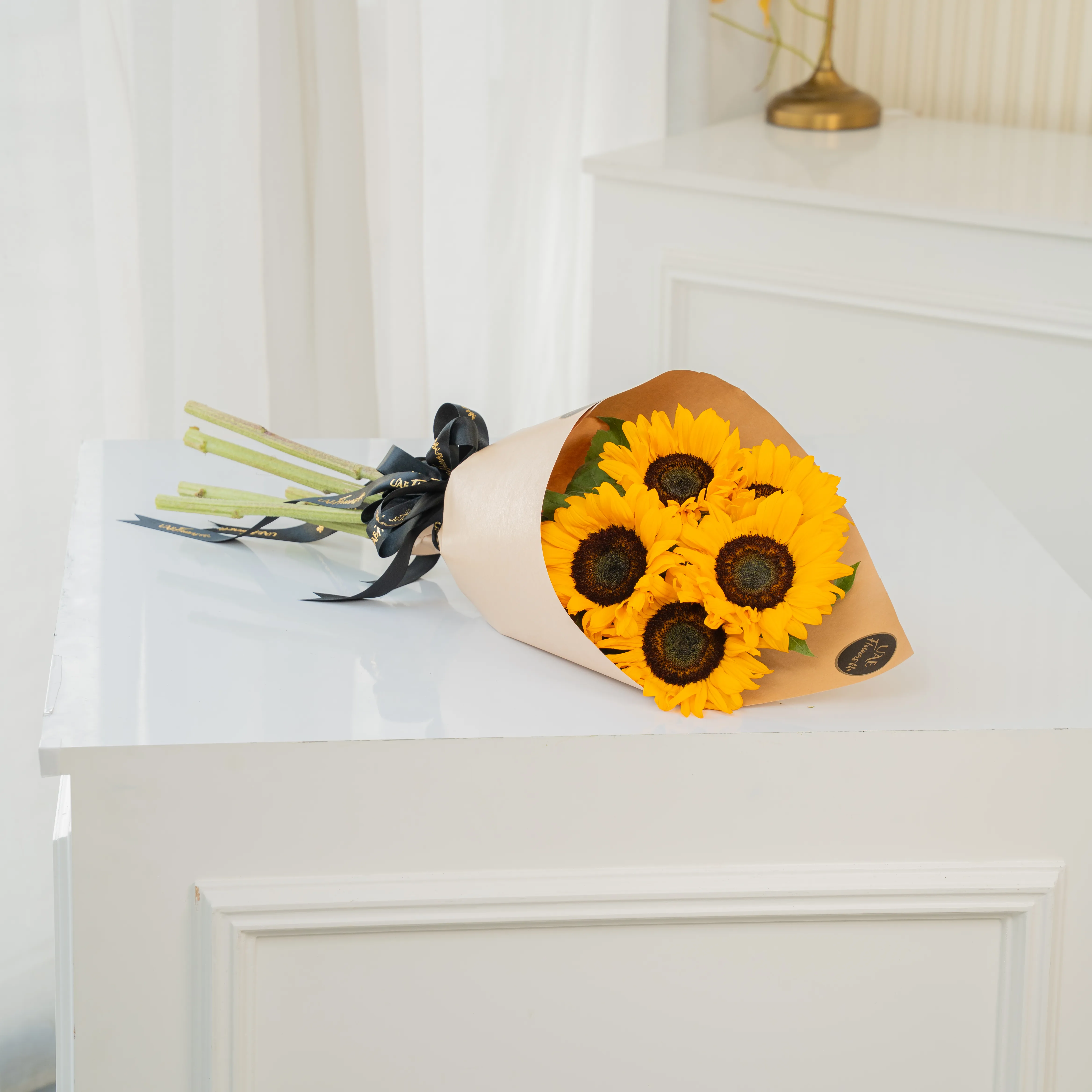 Bouquet of 5 sunflowers in paper packing hand-tied with ribbons.