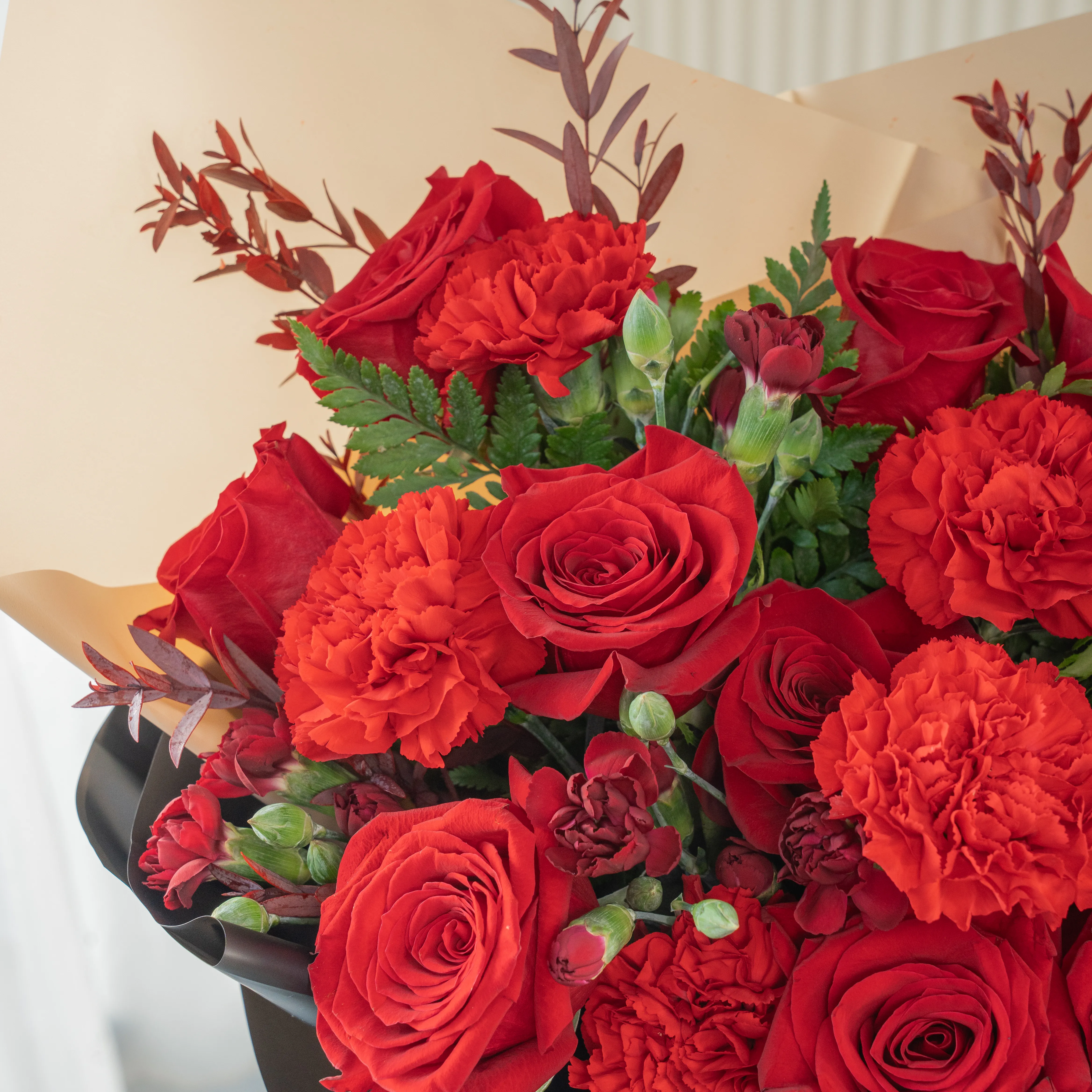 Bouquet of 12 red roses, 6 red carnations with green fillers in nice paper packing.