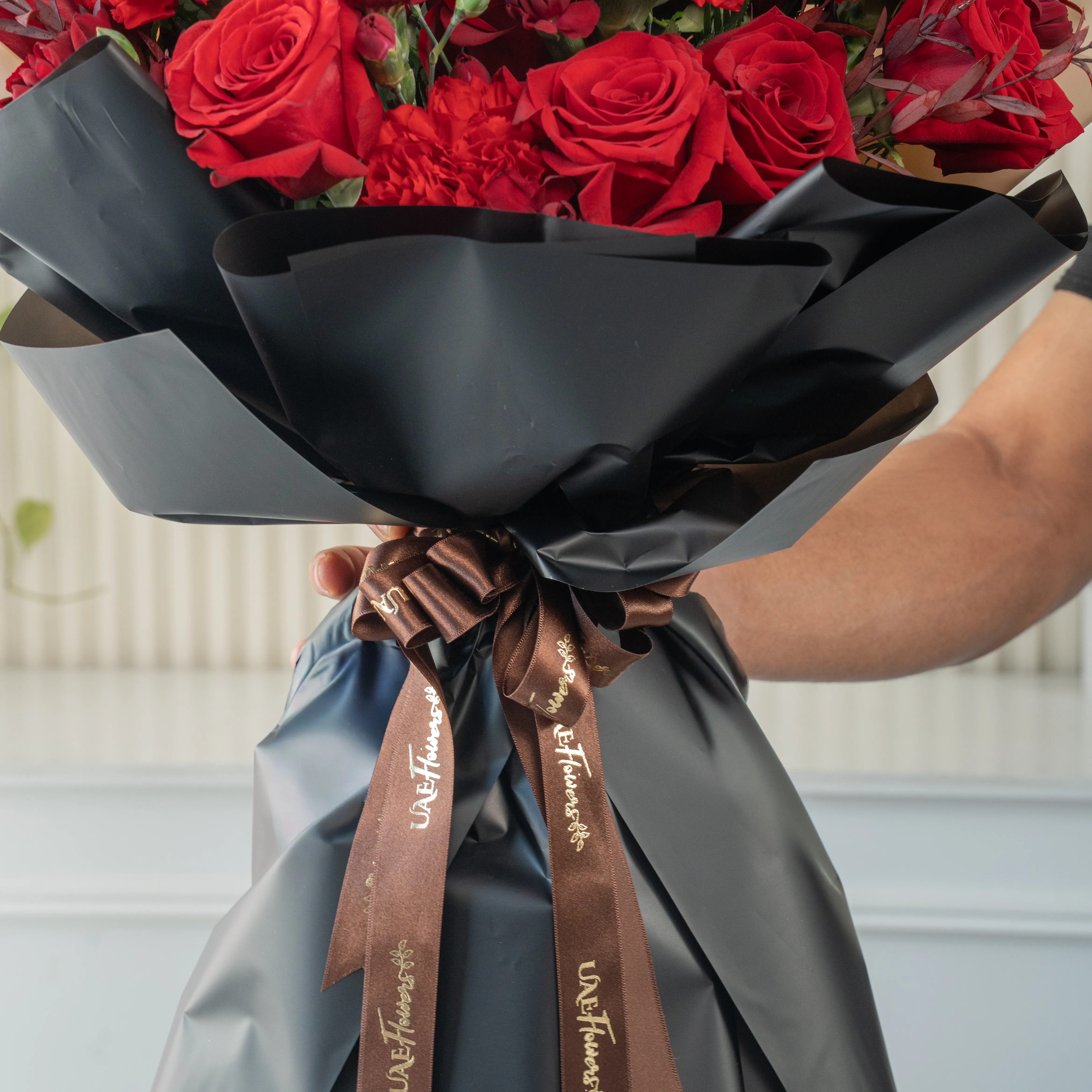 Bouquet of 12 red roses, 6 red carnations with green fillers in nice paper packing.