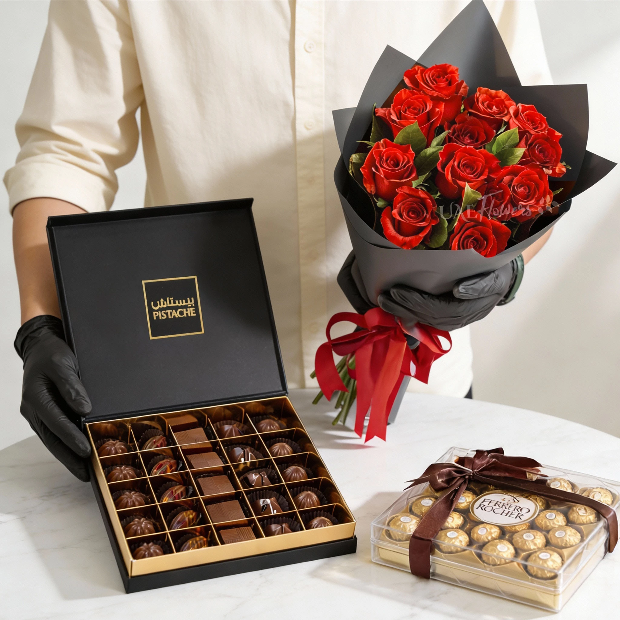 Bouquet of 12 red roses with green fillers in black paper packing tied with ribbons, 24pcs of Ferrero Rocher chocolate and 25 Pcs Pistache Signature Temptation Chocolate Box.
