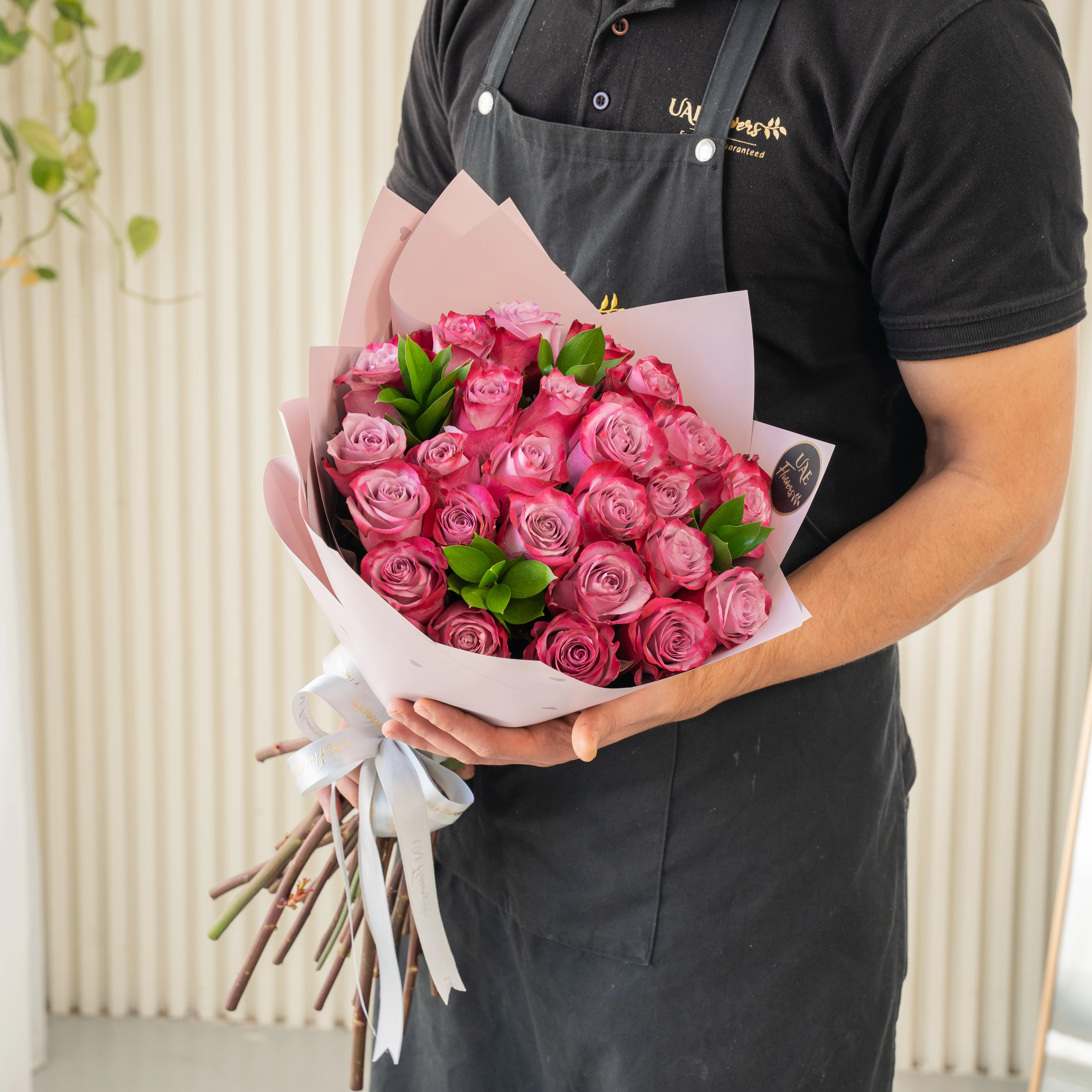 Bouquet of 20 purple roses in paper packing hand-tied with ribbons.