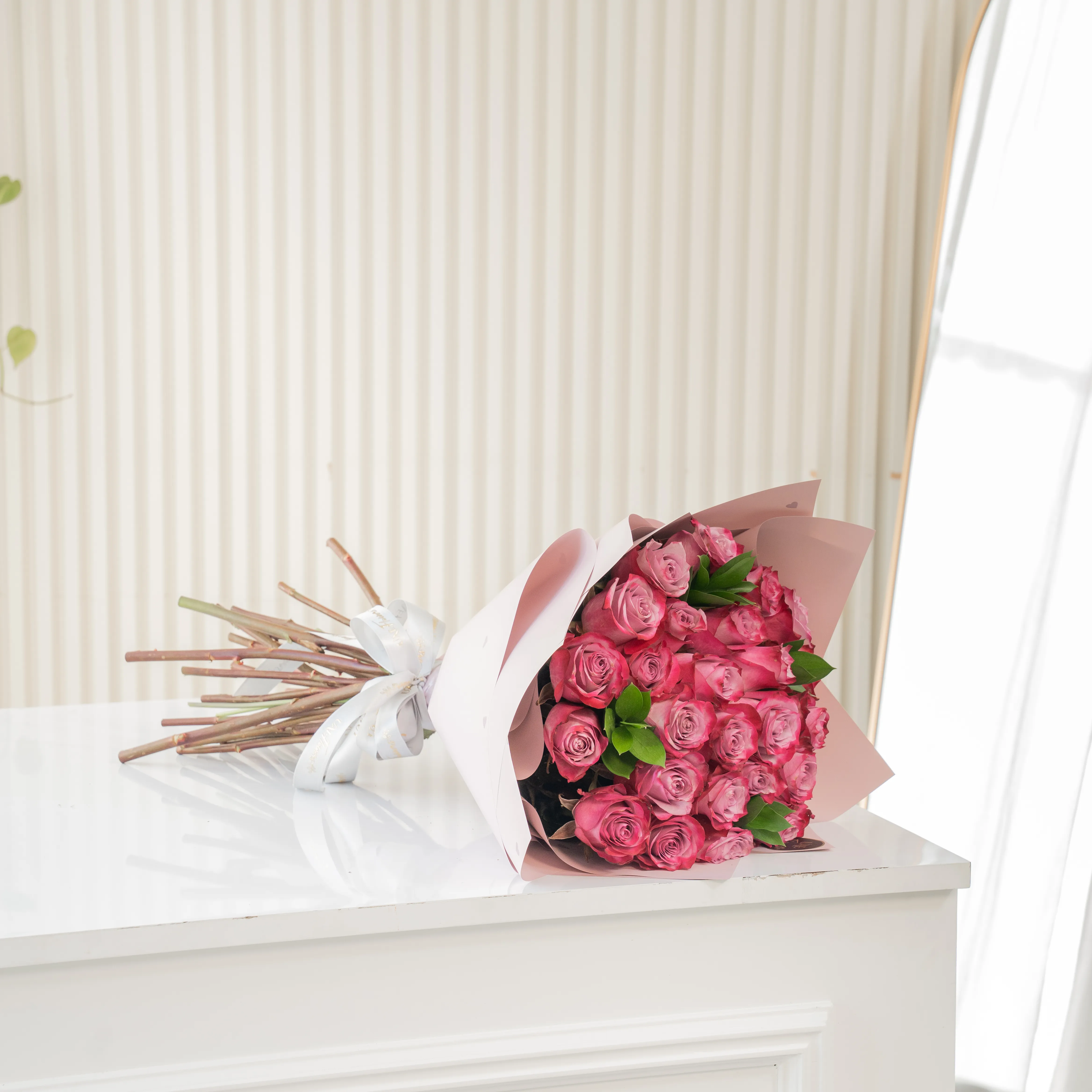 Bouquet of 20 purple roses in paper packing hand-tied with ribbons.