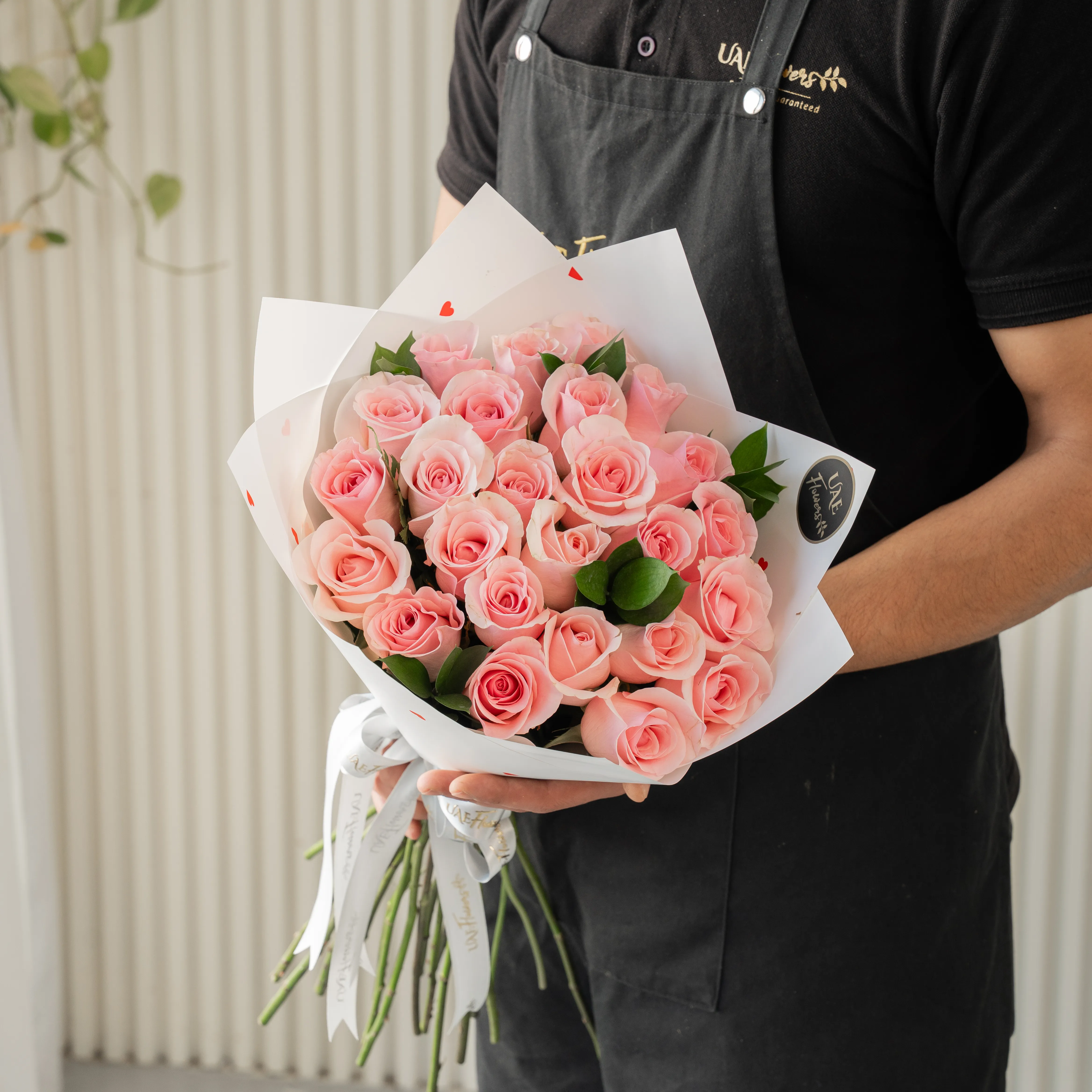 Bouquet of 20 pink roses in paper packing hand-tied with ribbons.