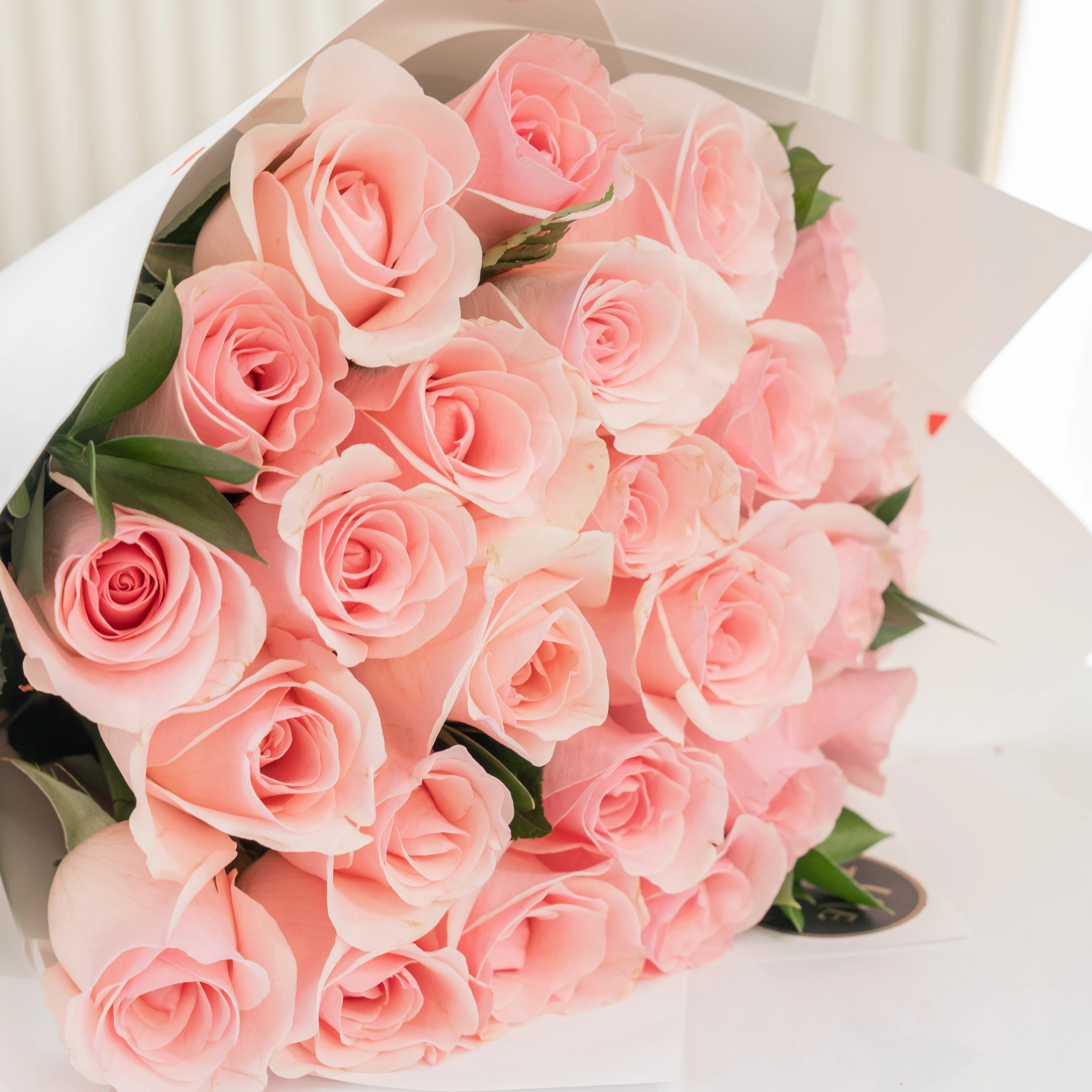Bouquet of 20 pink roses in paper packing hand-tied with ribbons.