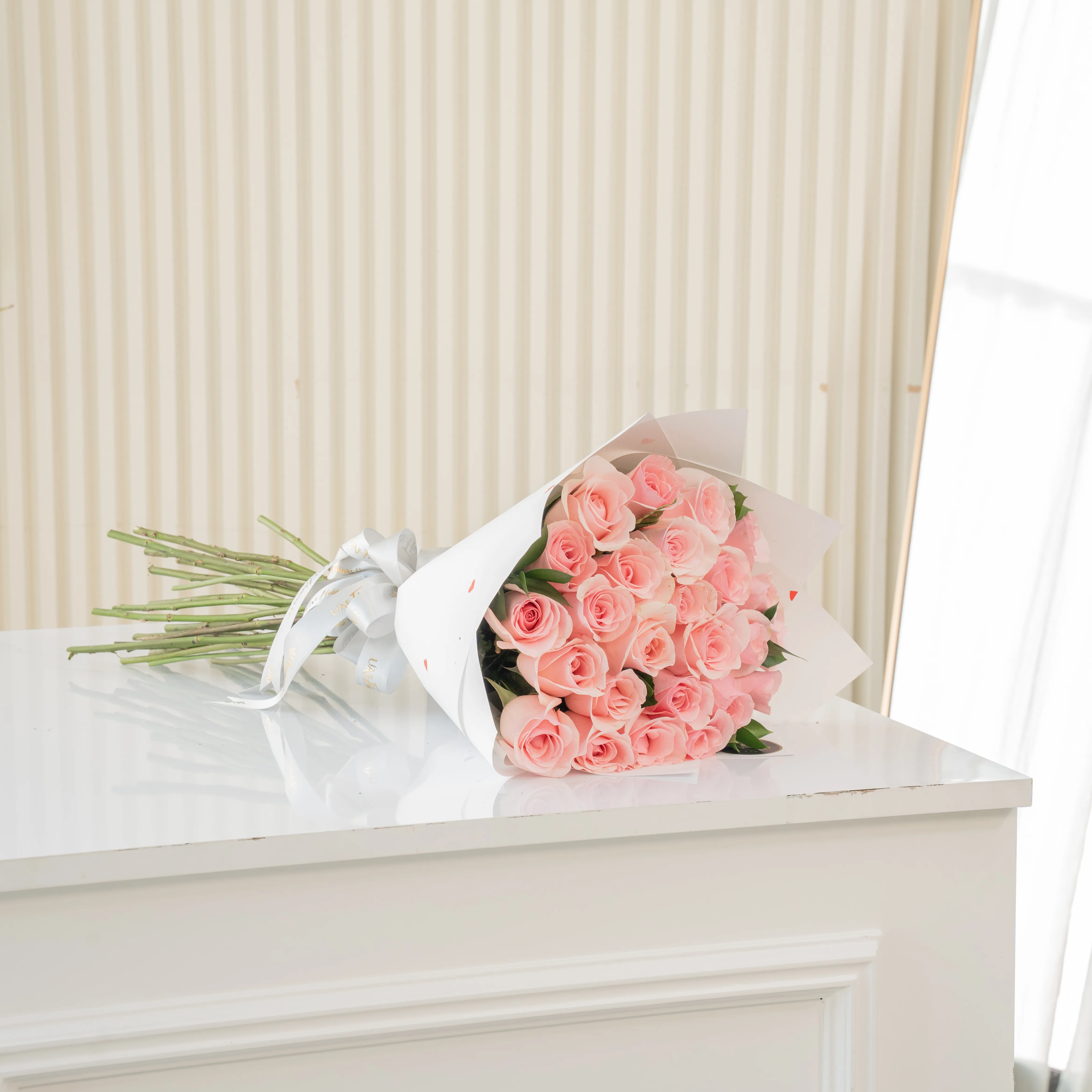 Bouquet of 20 pink roses in paper packing hand-tied with ribbons.
