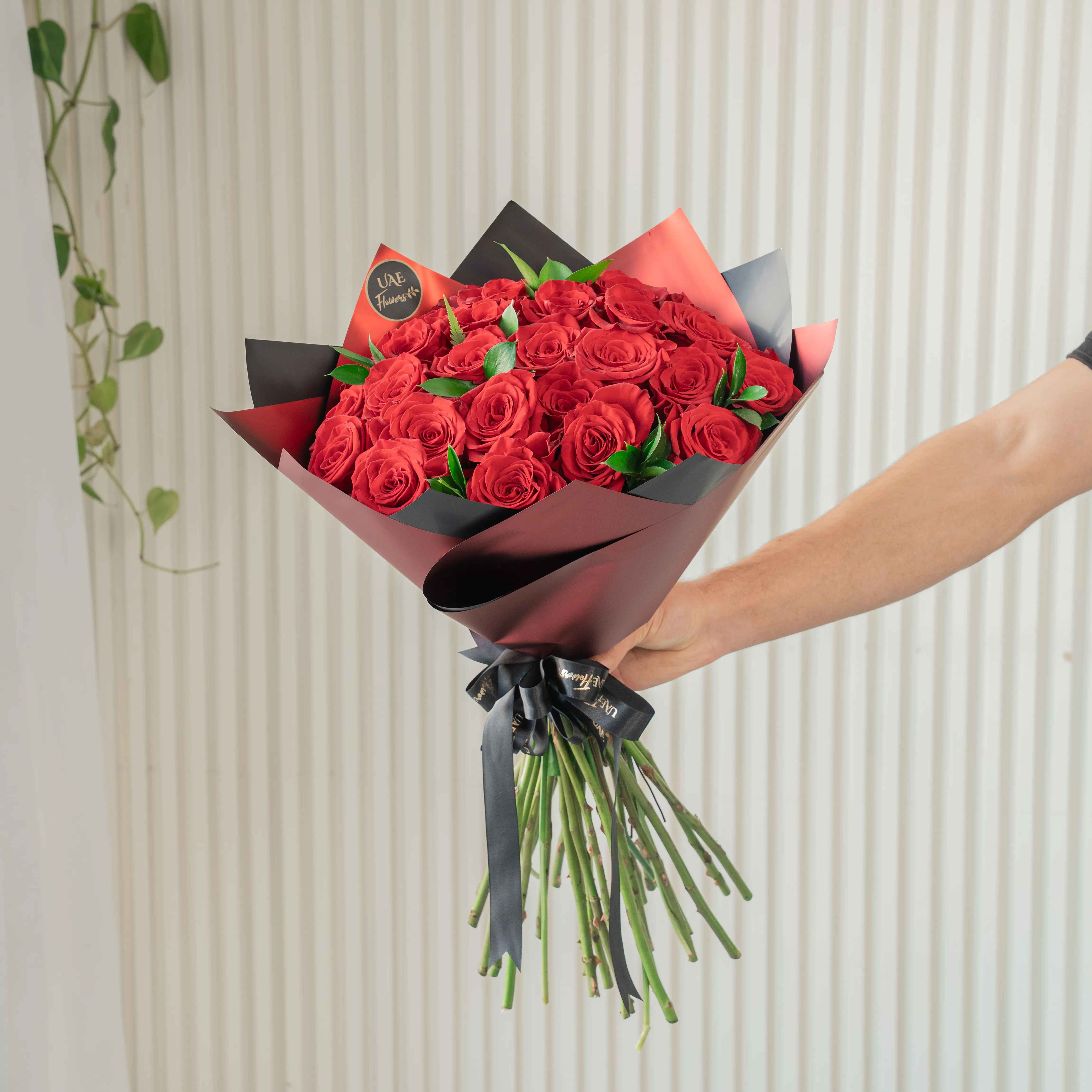 Bouquet of 20 red roses in paper packing hand-tied with ribbons.