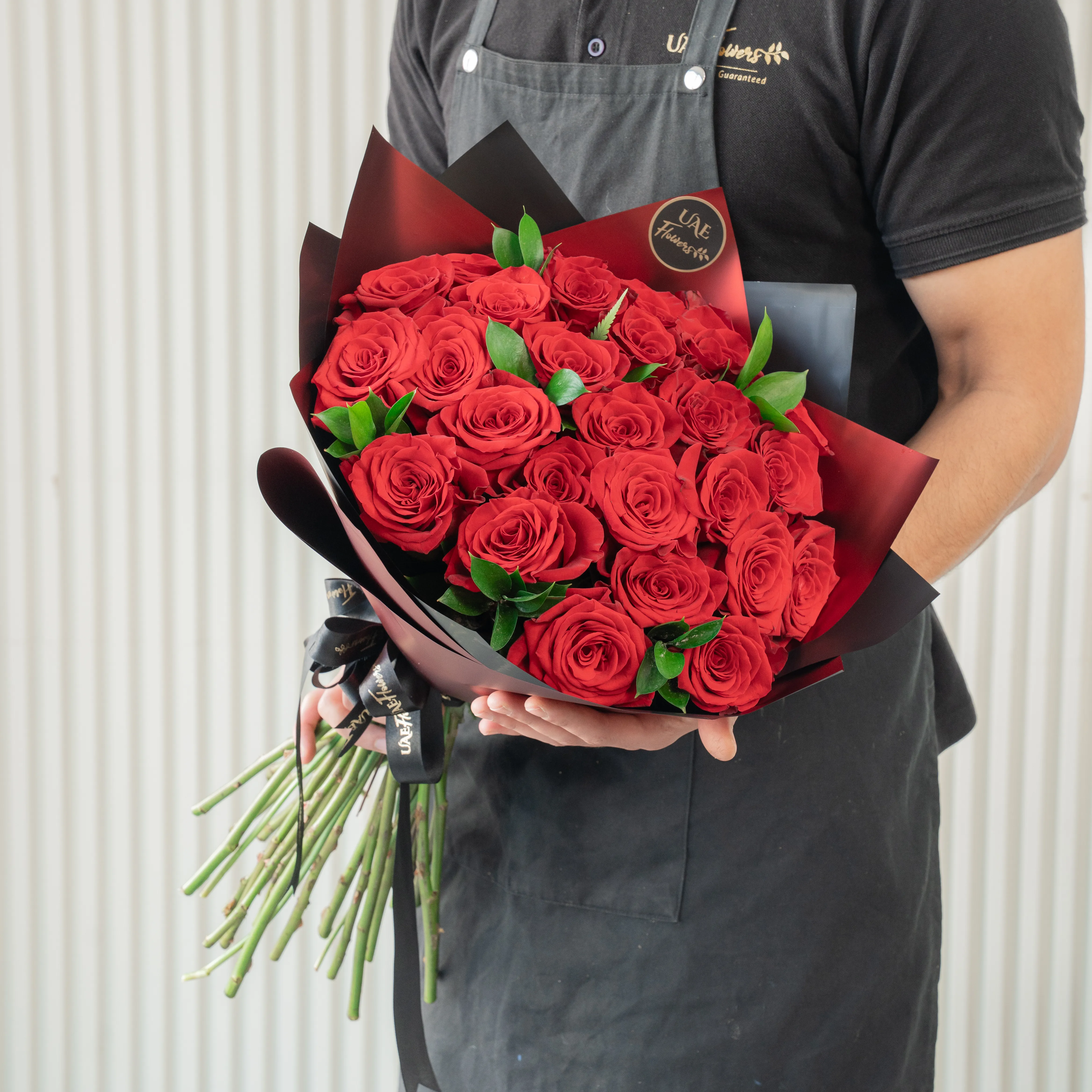 Bouquet of 20 red roses in paper packing hand-tied with ribbons.