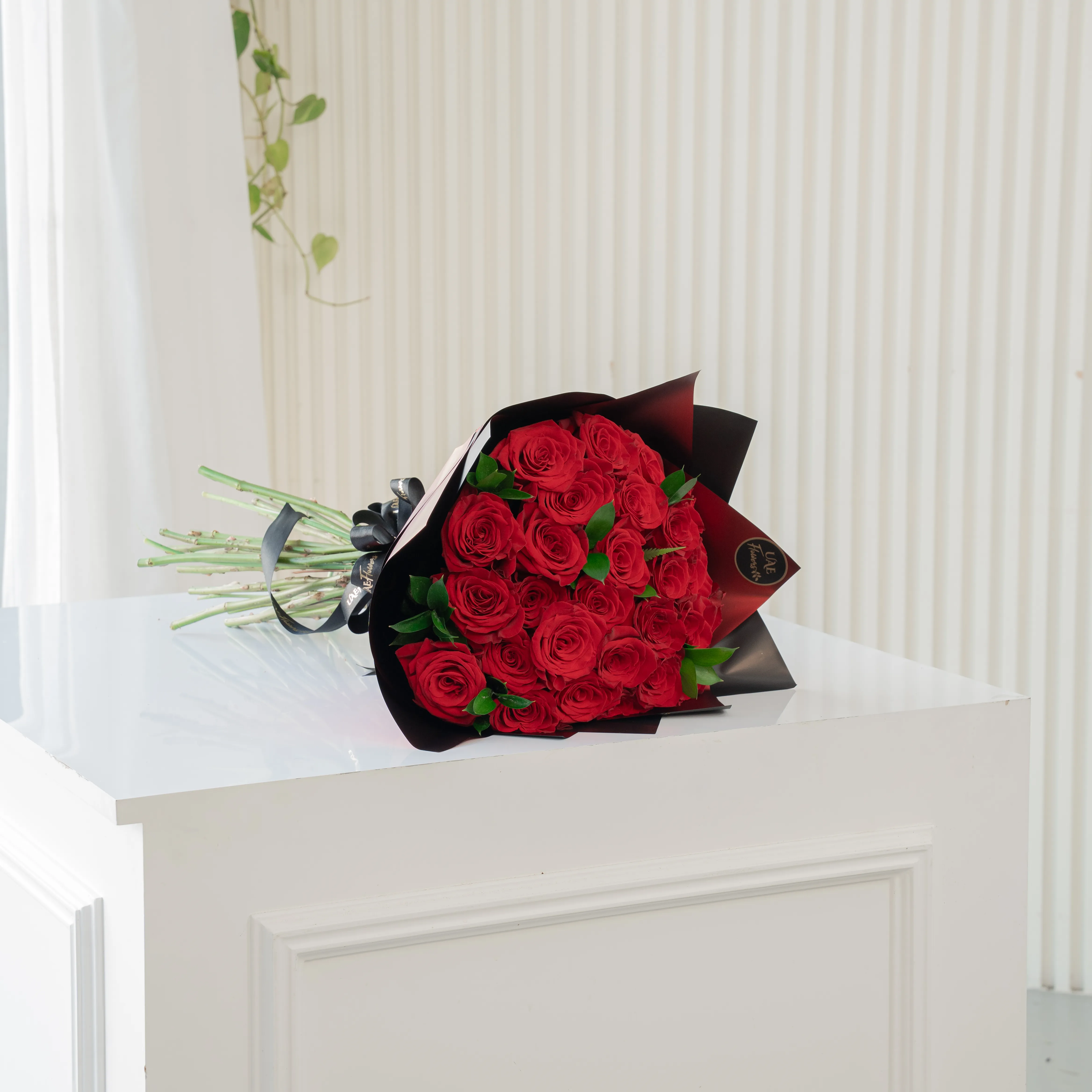 Bouquet of 20 red roses in paper packing hand-tied with ribbons.