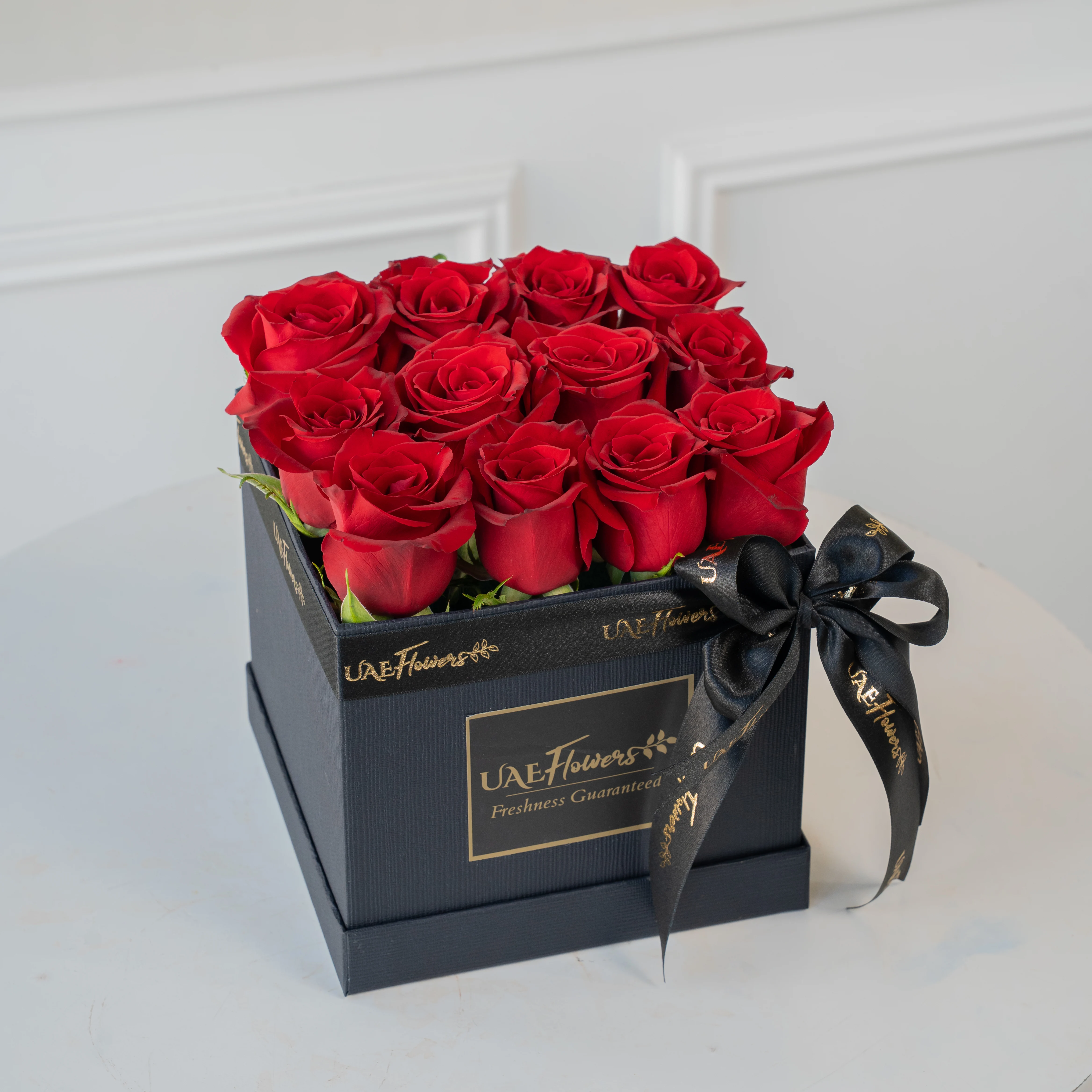 An Arrangement of 12 Red Roses in a Square Black Box