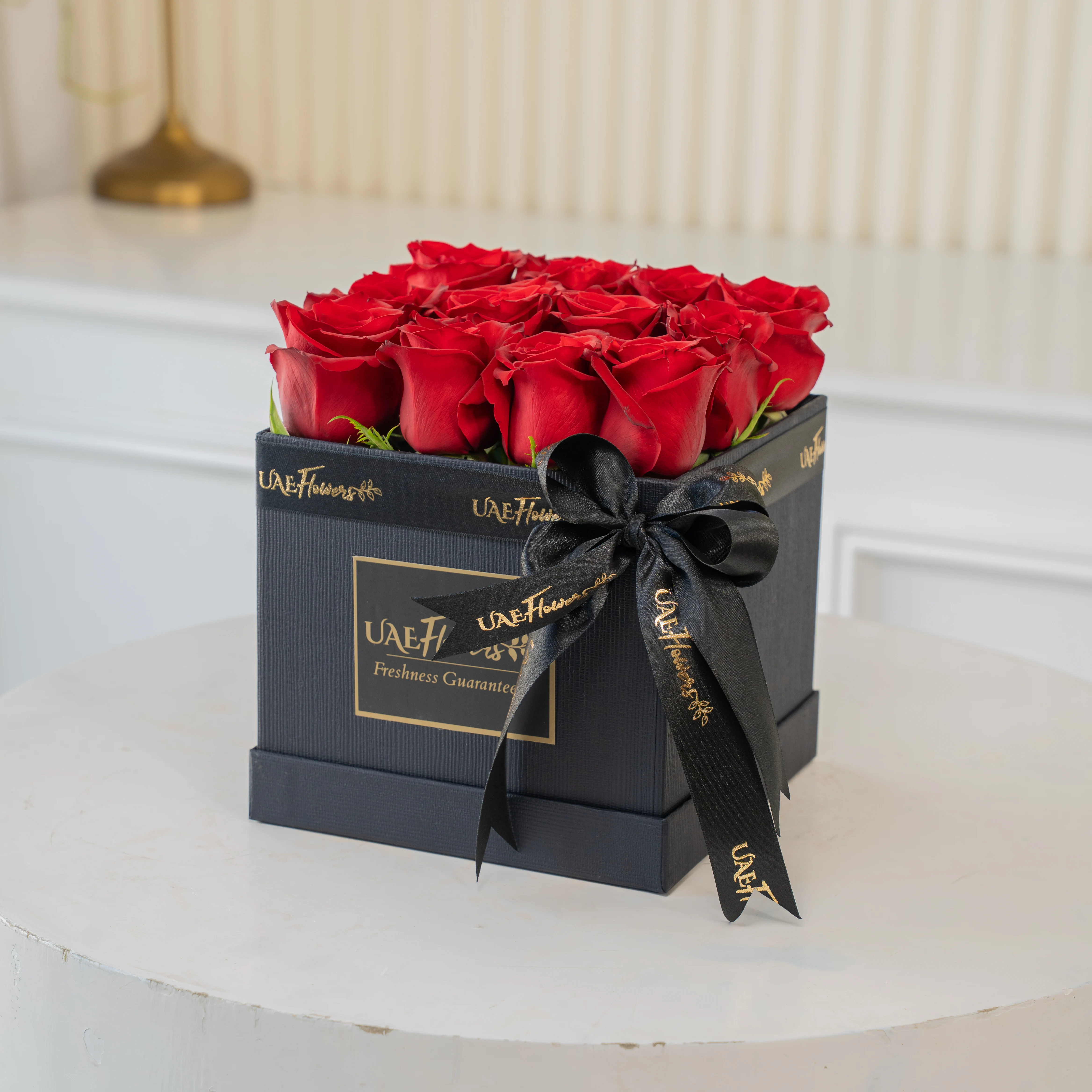 An Arrangement of 12 Red Roses in a Square Black Box